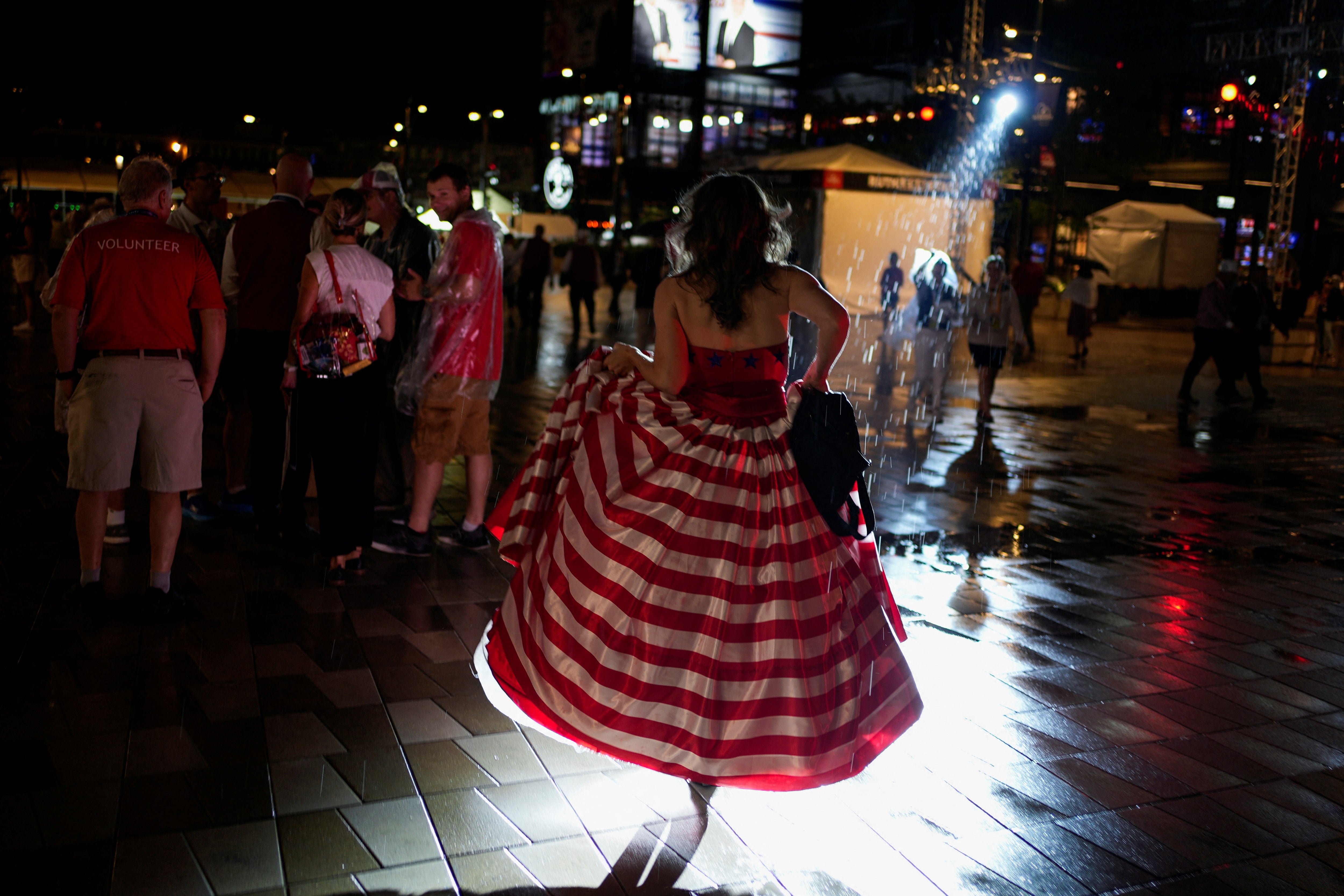 An attendee walks in the rain in a striped red and white ballgown