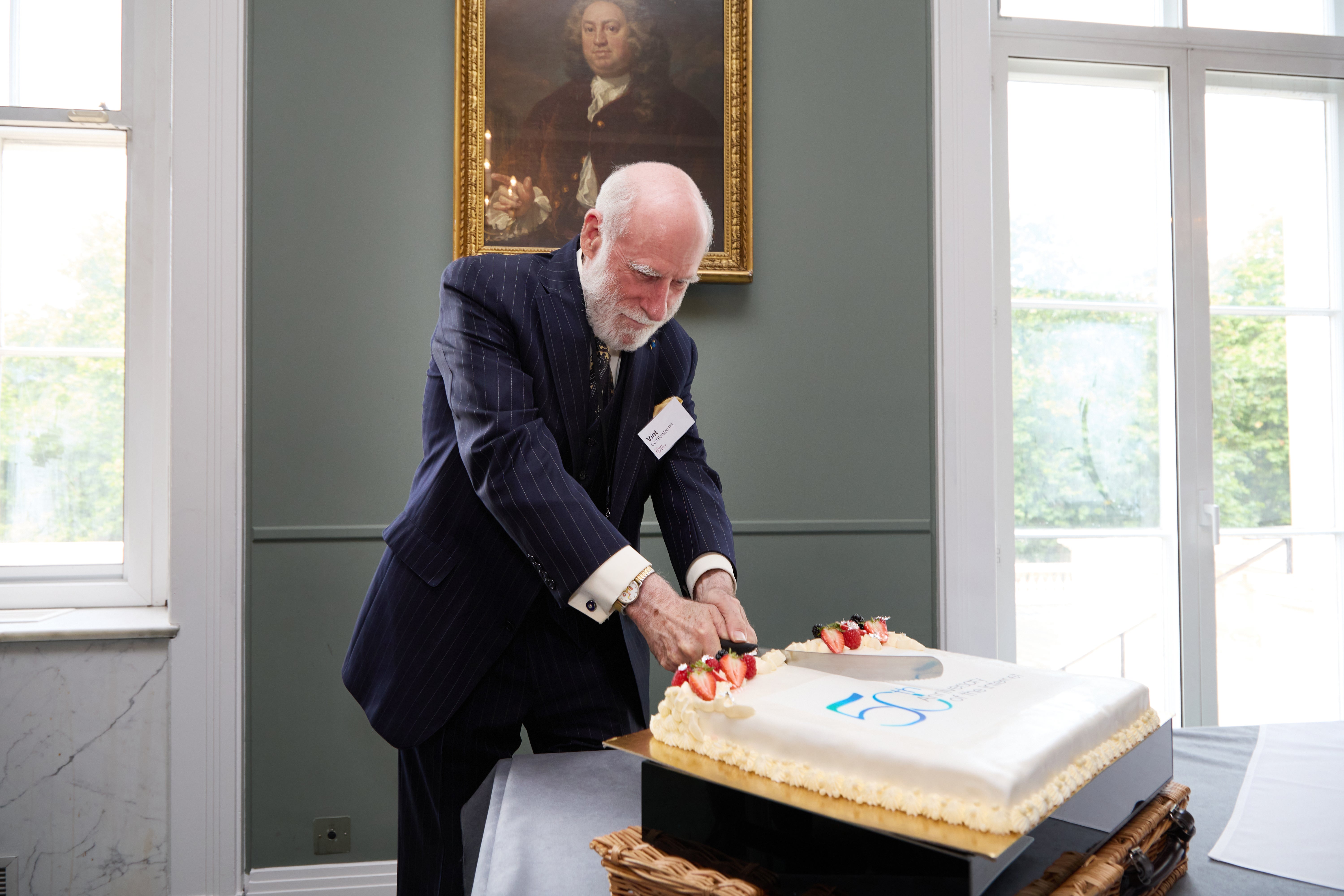 Vint Cerf cuts a cake to celebrate 50 years of the internet