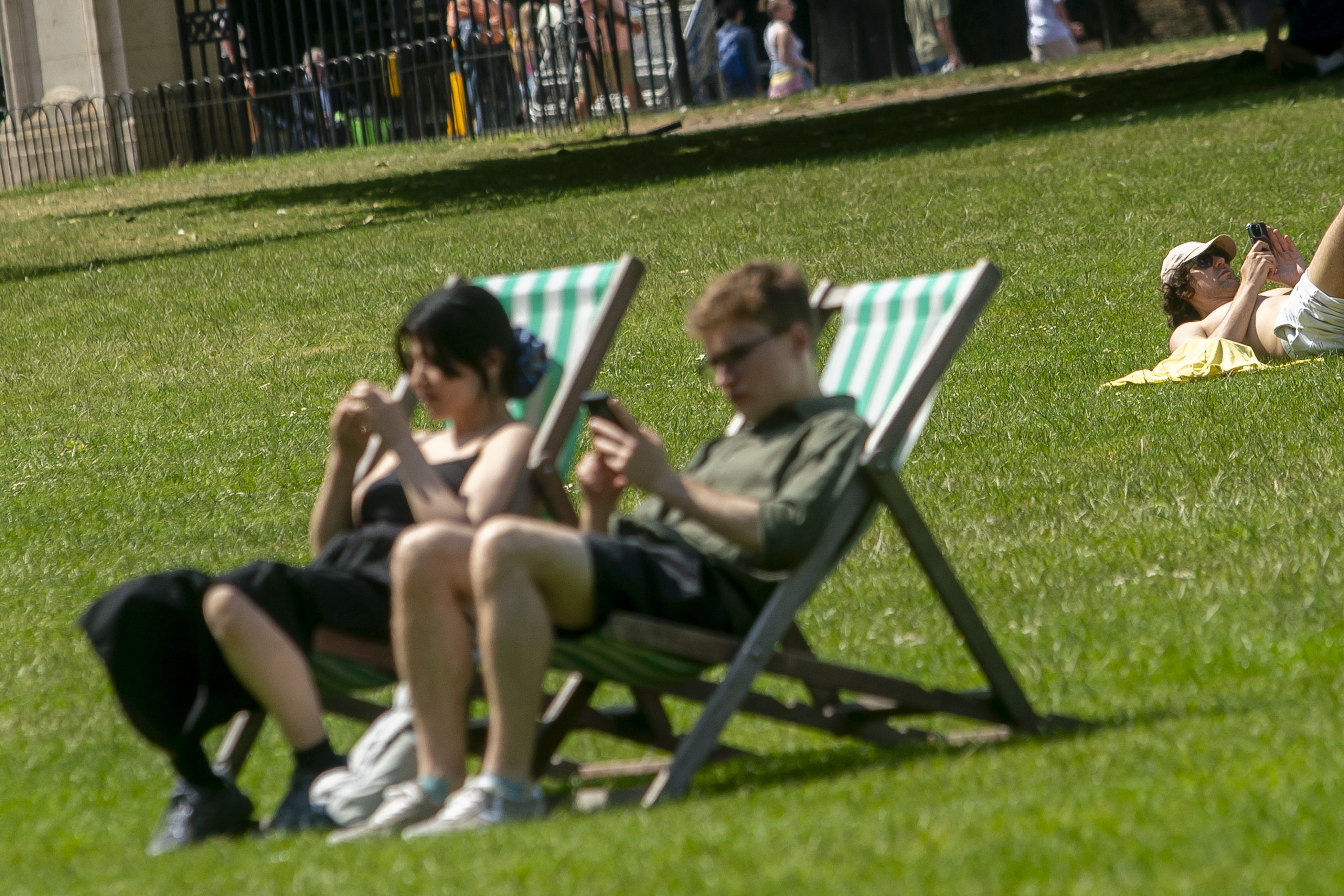 Members of the public enjoy the summer sun in Green Park in London (Jeff Moore/PA)