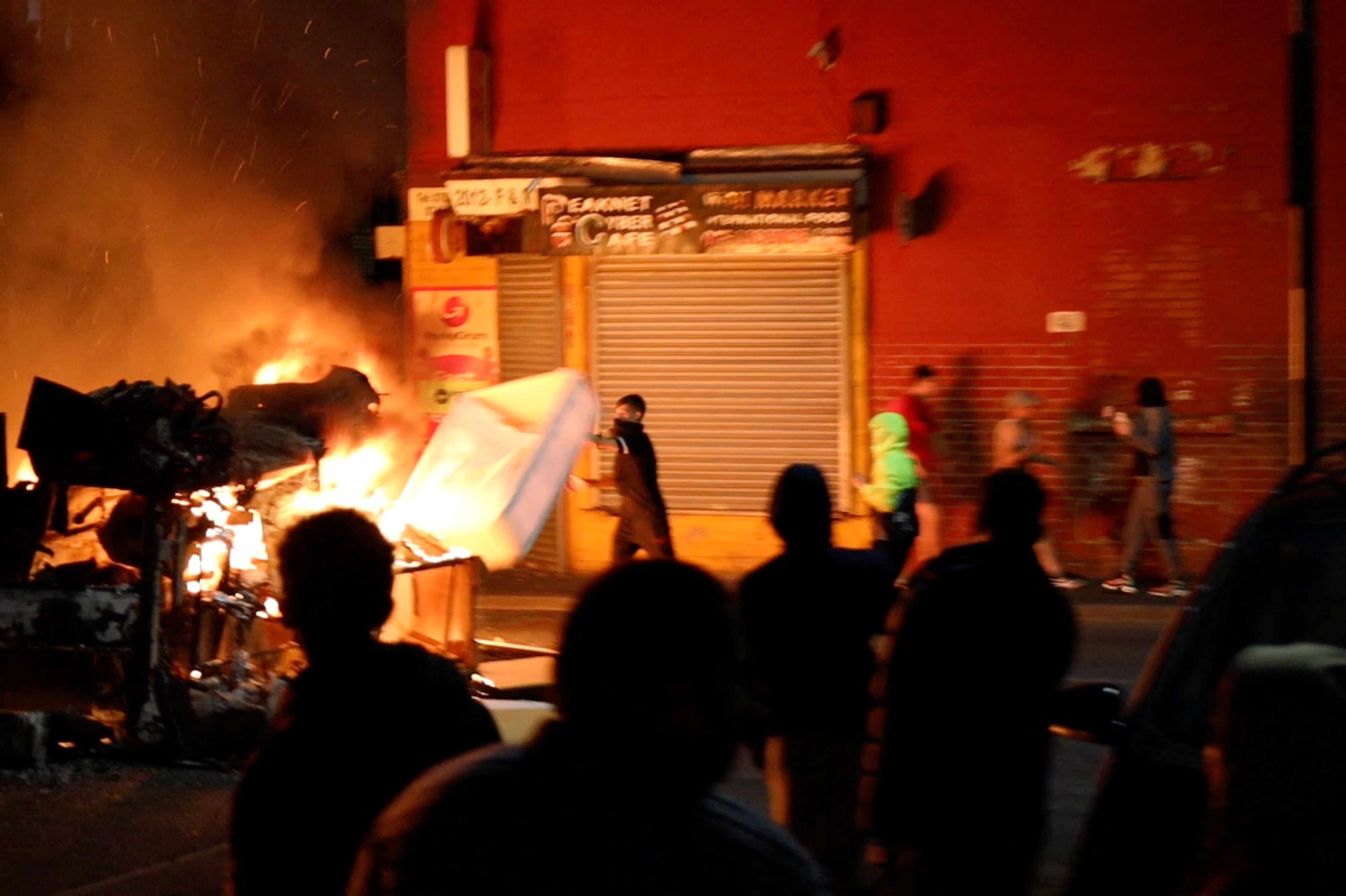 A man throws an item onto a fire during unrest in Harehills