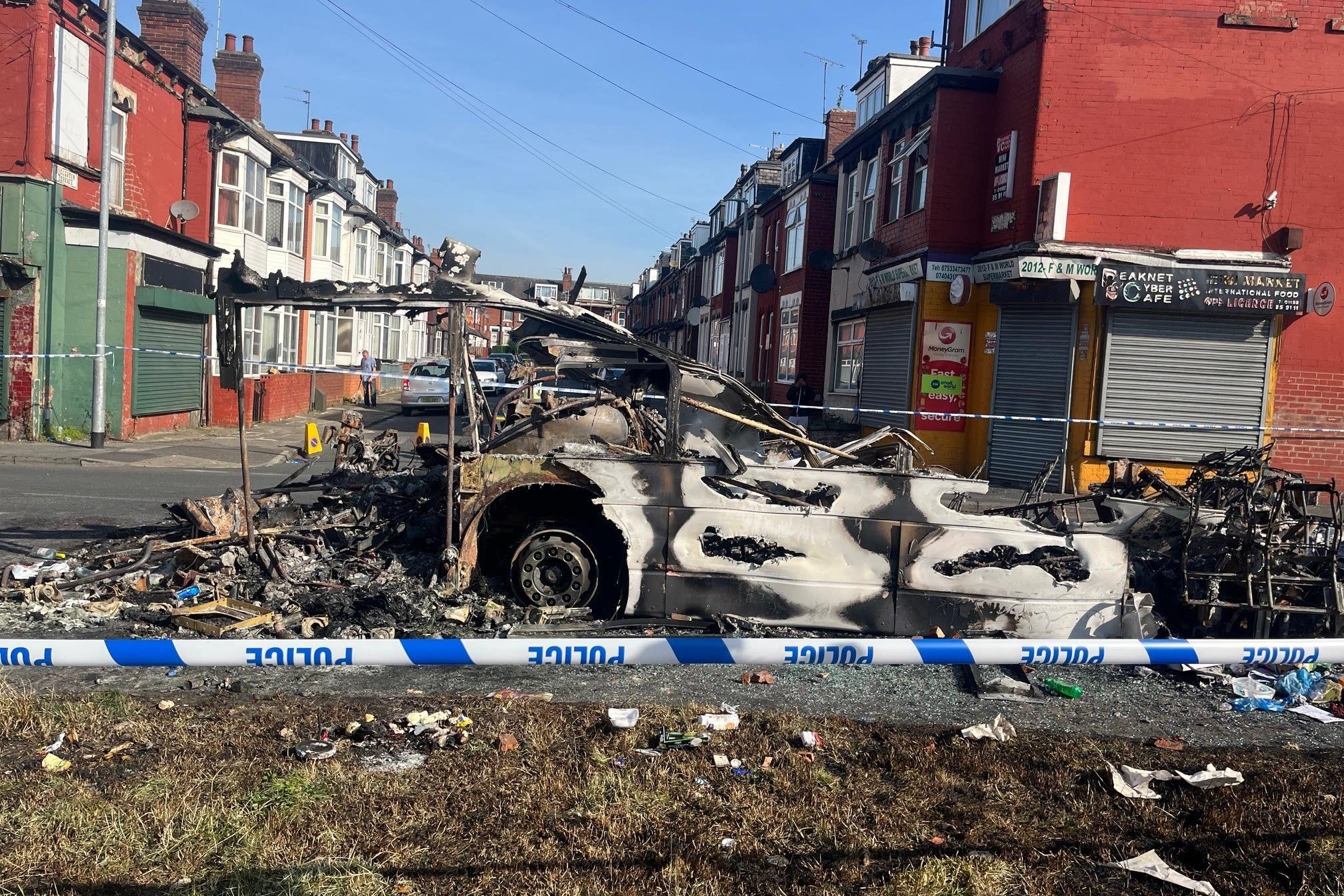 A burnt out car behind police tape in Harehills (Katie Dickinson/PA)