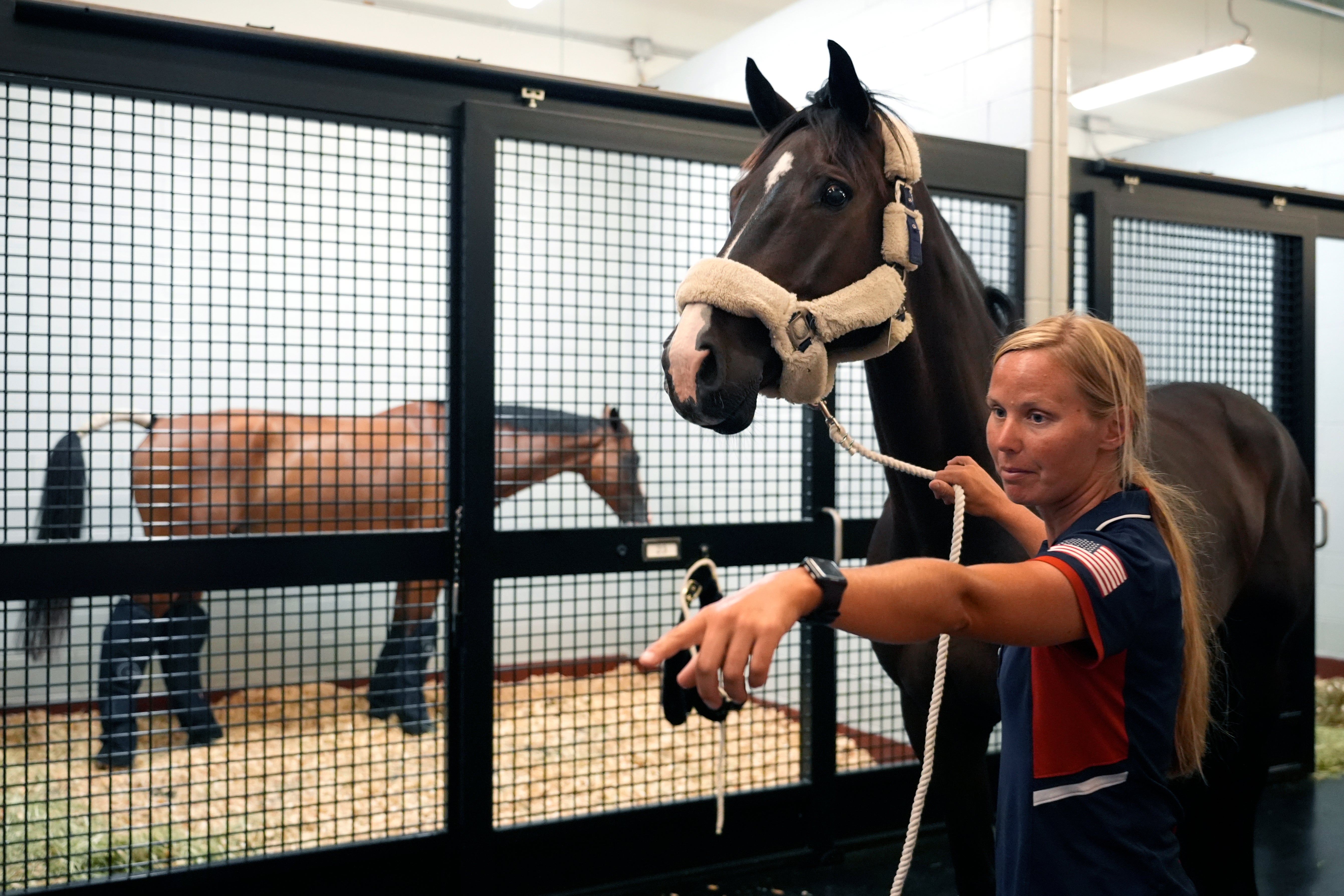 Stephanie Simpson, groom for U.S. Olympic Eventing Team member Boyd Martin, directs a team horse to a cargo stall at The Ark