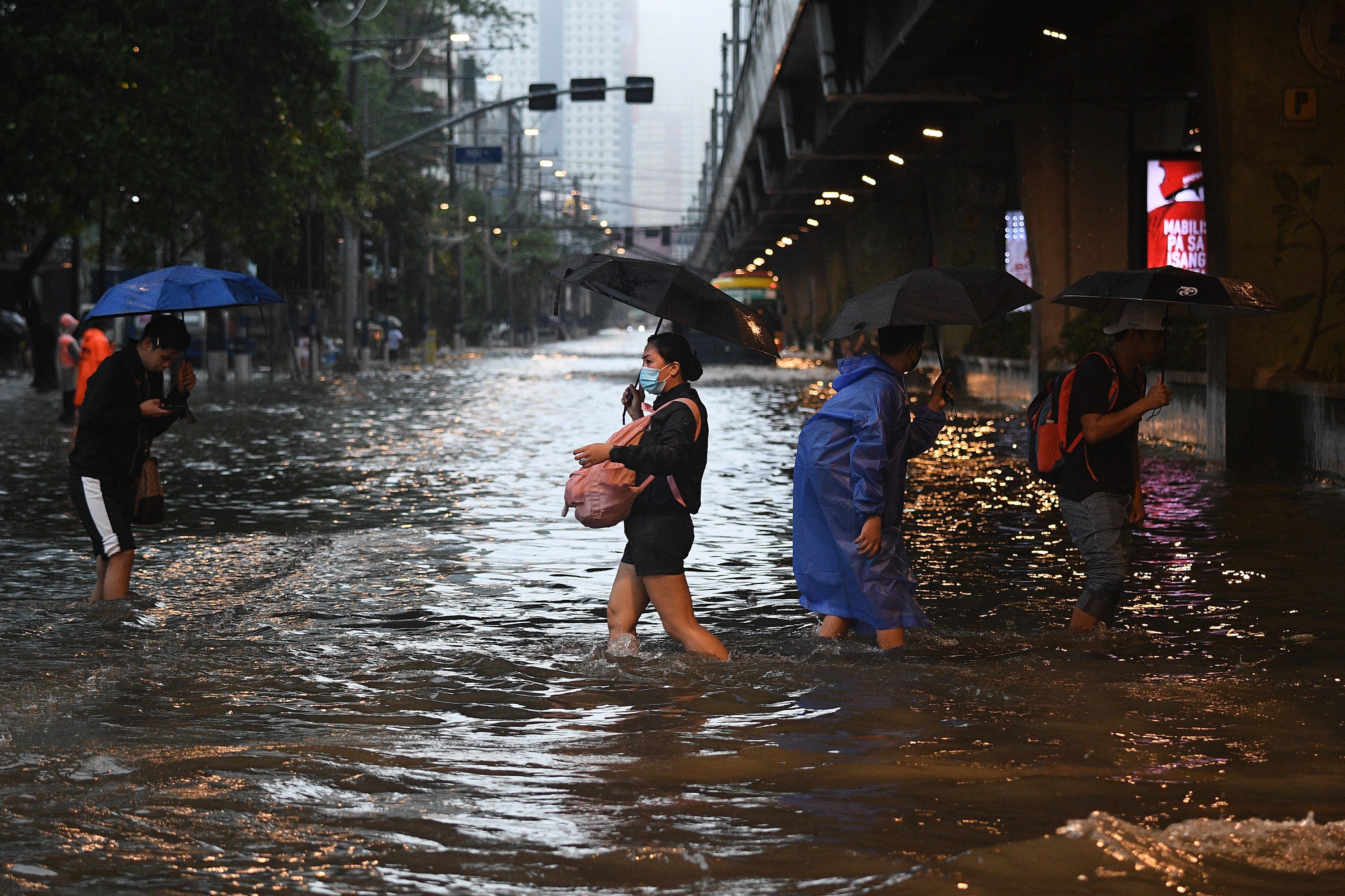 Pedestrians cross a flooded street in Manila amid heavy rains brought by Typhoon Gaemi.