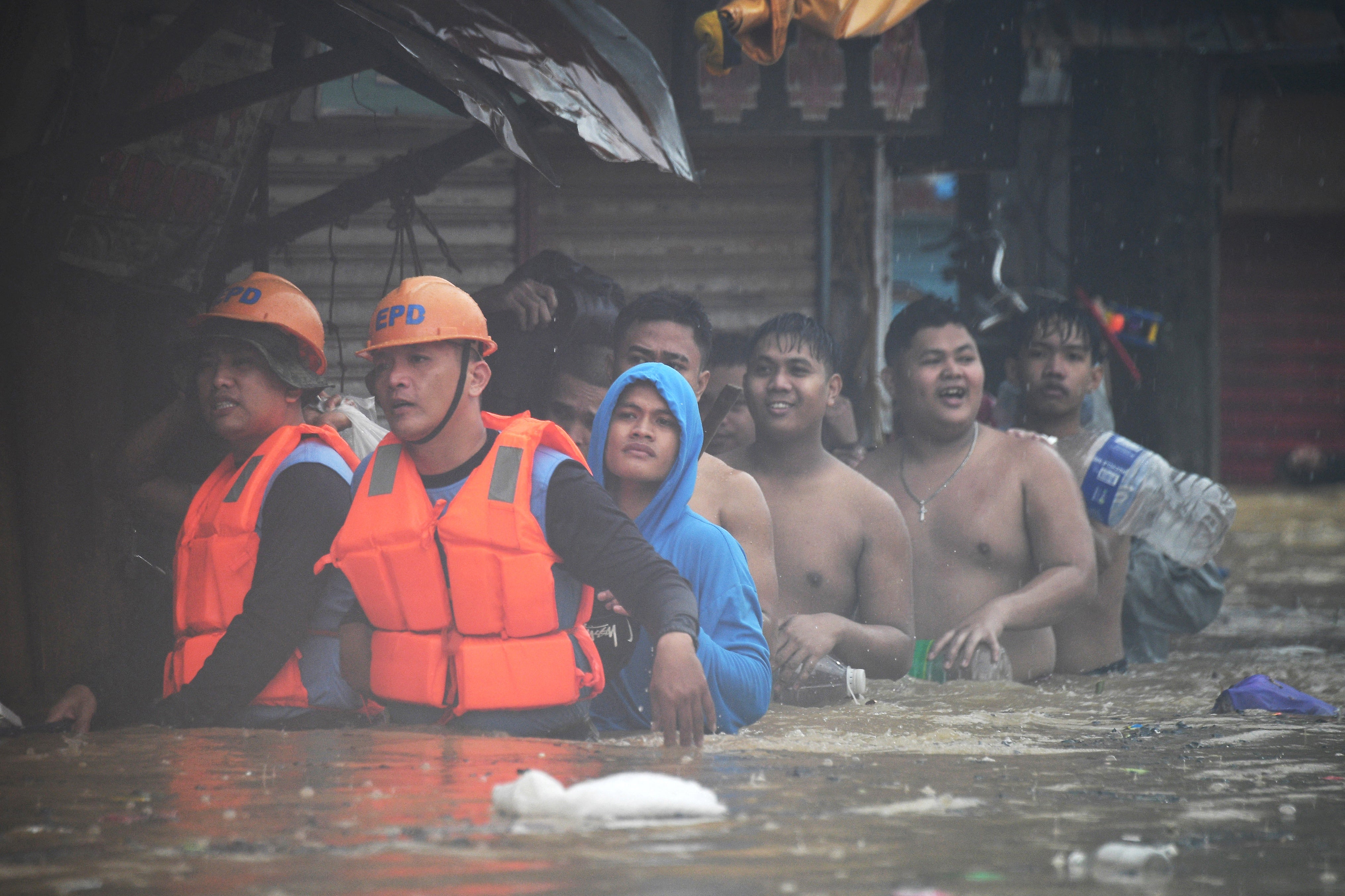 Rescuers (front L) guide residents with their belongings as they evacuate from their flooded homes in Tumana village, Marikina City, east of Manila