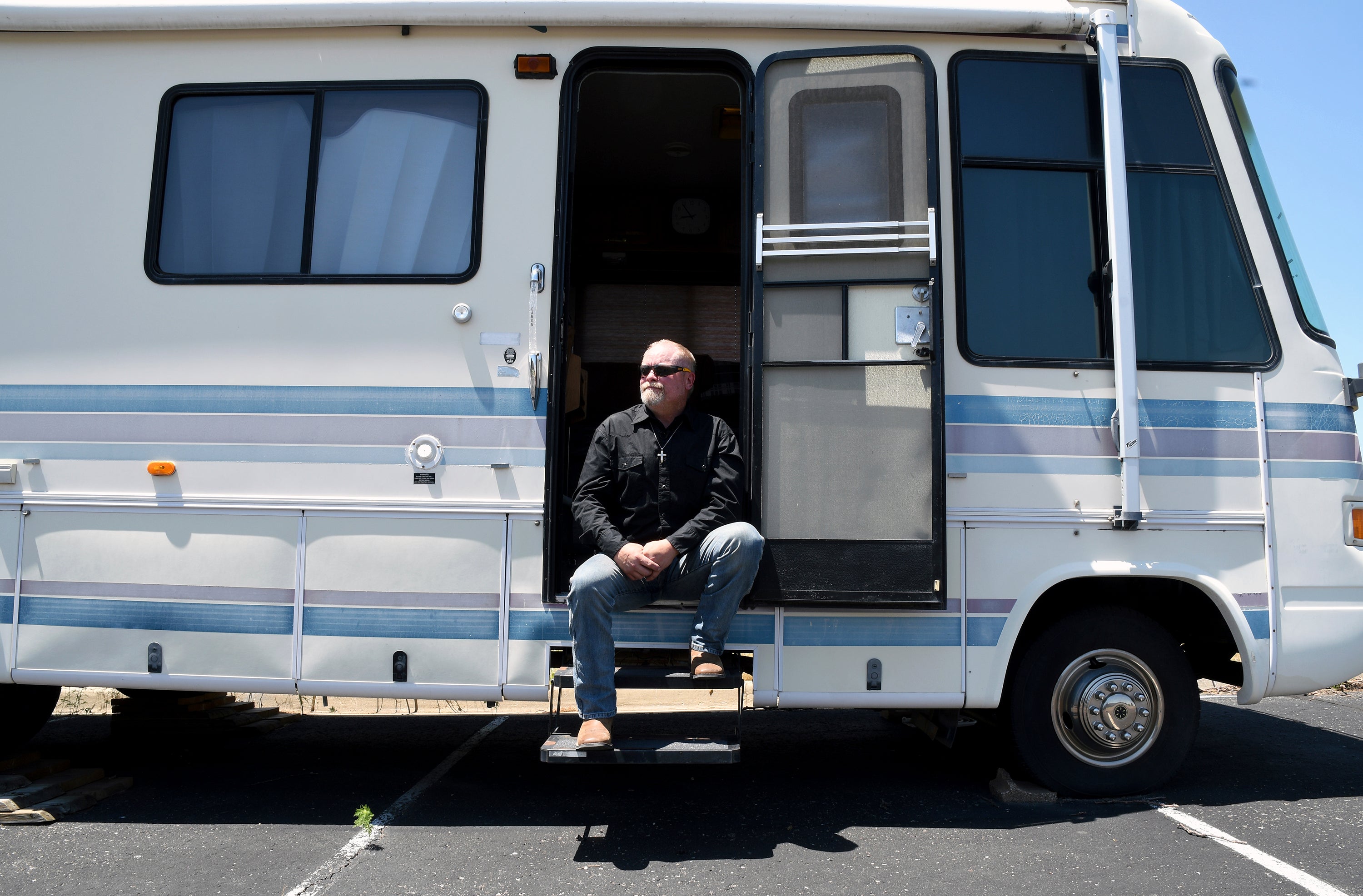 Joe Ridenour sits for a portrait on the steps of the recreational vehicle he once called home in Castle Rock