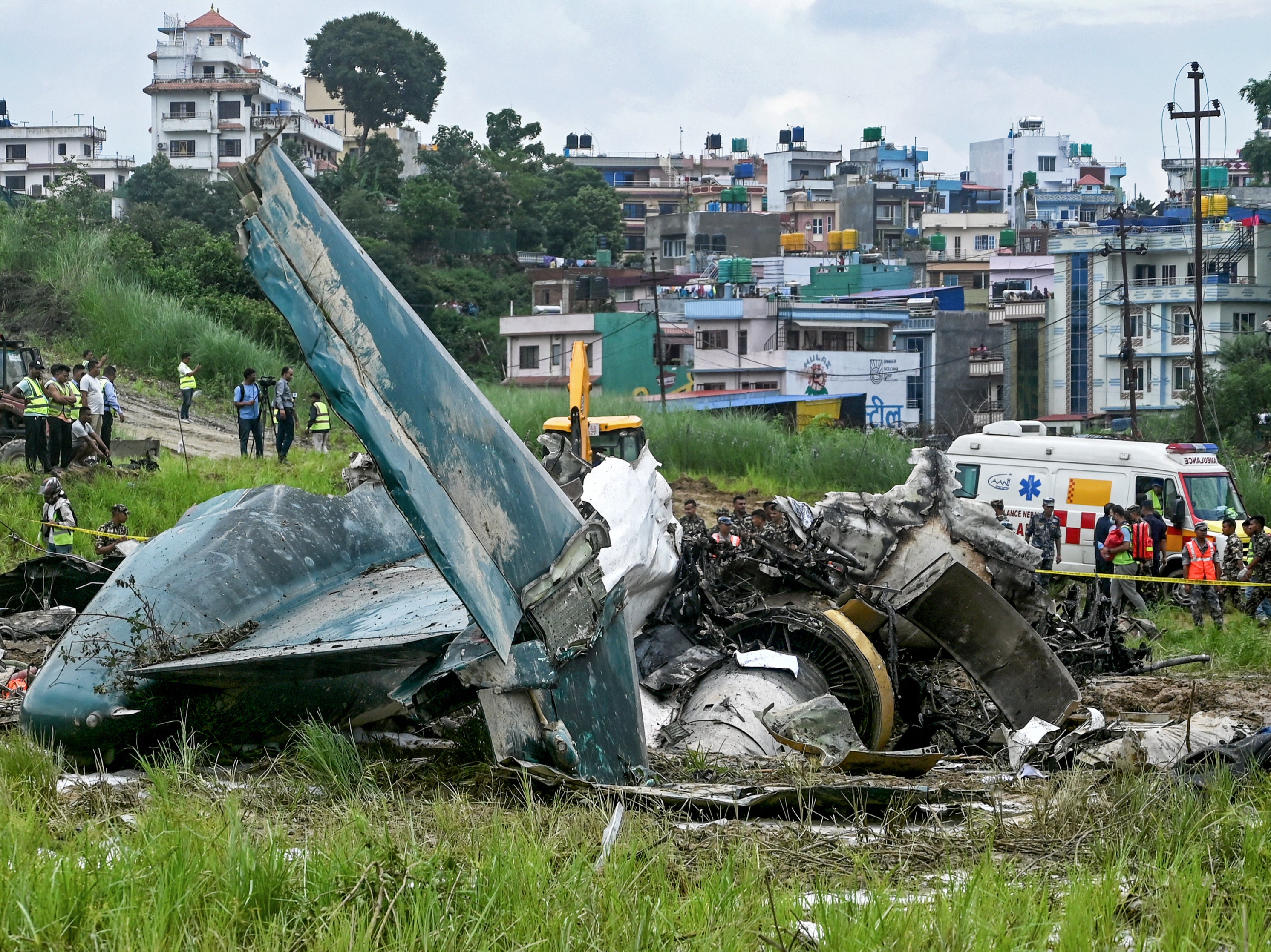 Security personnel inspect the remains of the crashed Saurya Airlines plane