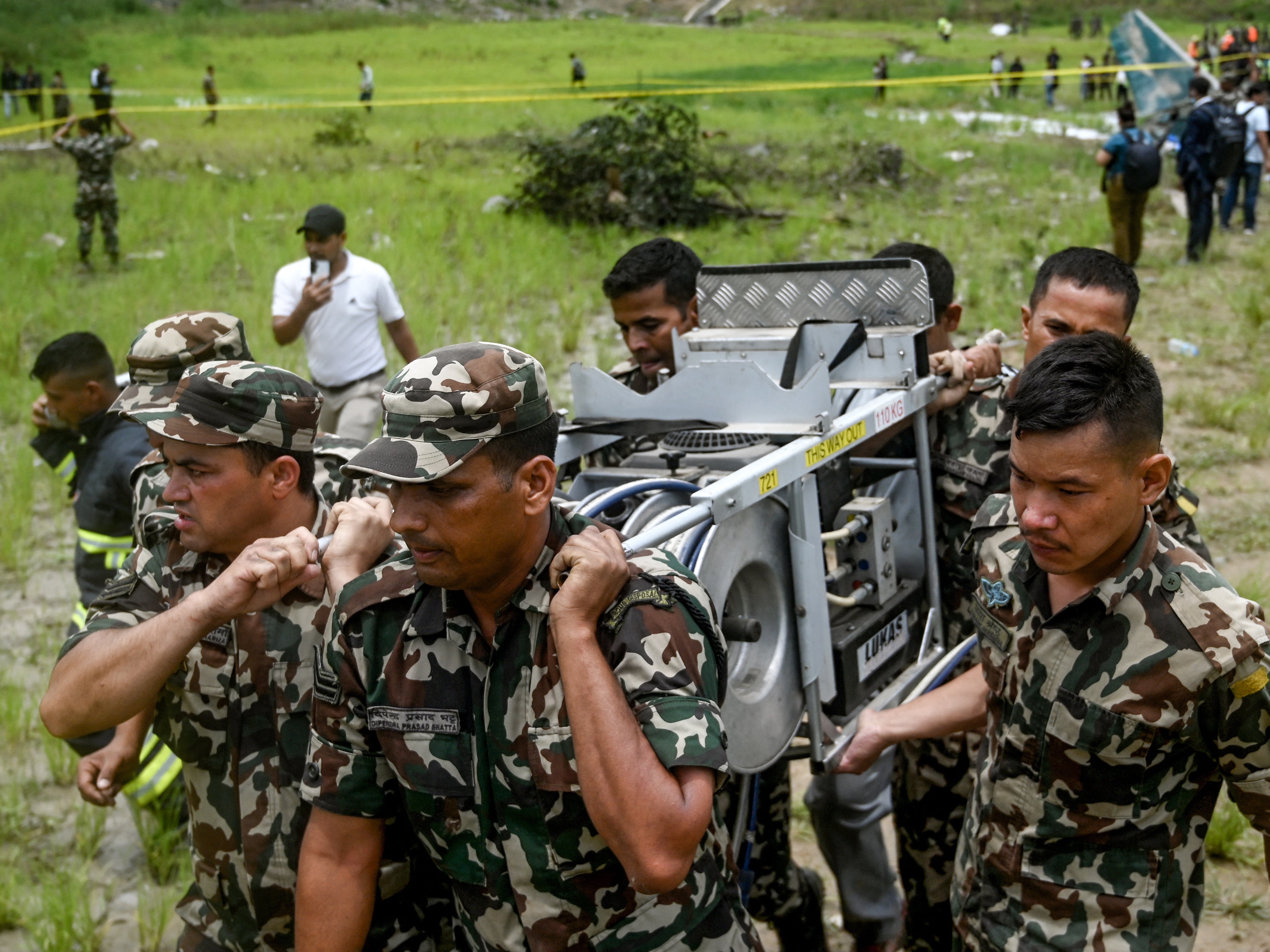 Security personnel carry the wreckage of the Saurya Airlines plane