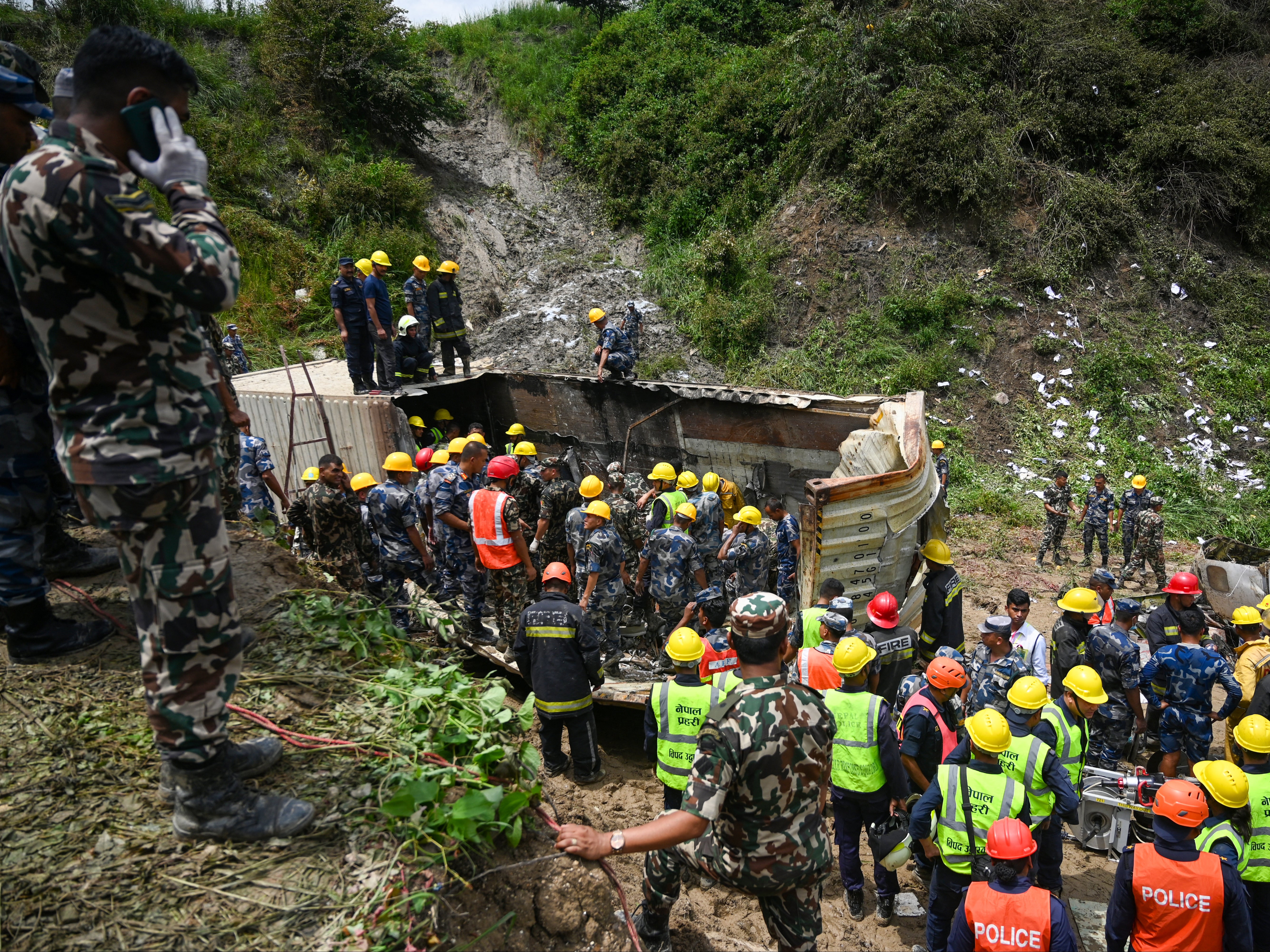 Security and rescue personnel clear the debris of the Saurya Airlines plane after it crashed at the Tribhuvan International Airport in Kathmandu on 24 July 2024