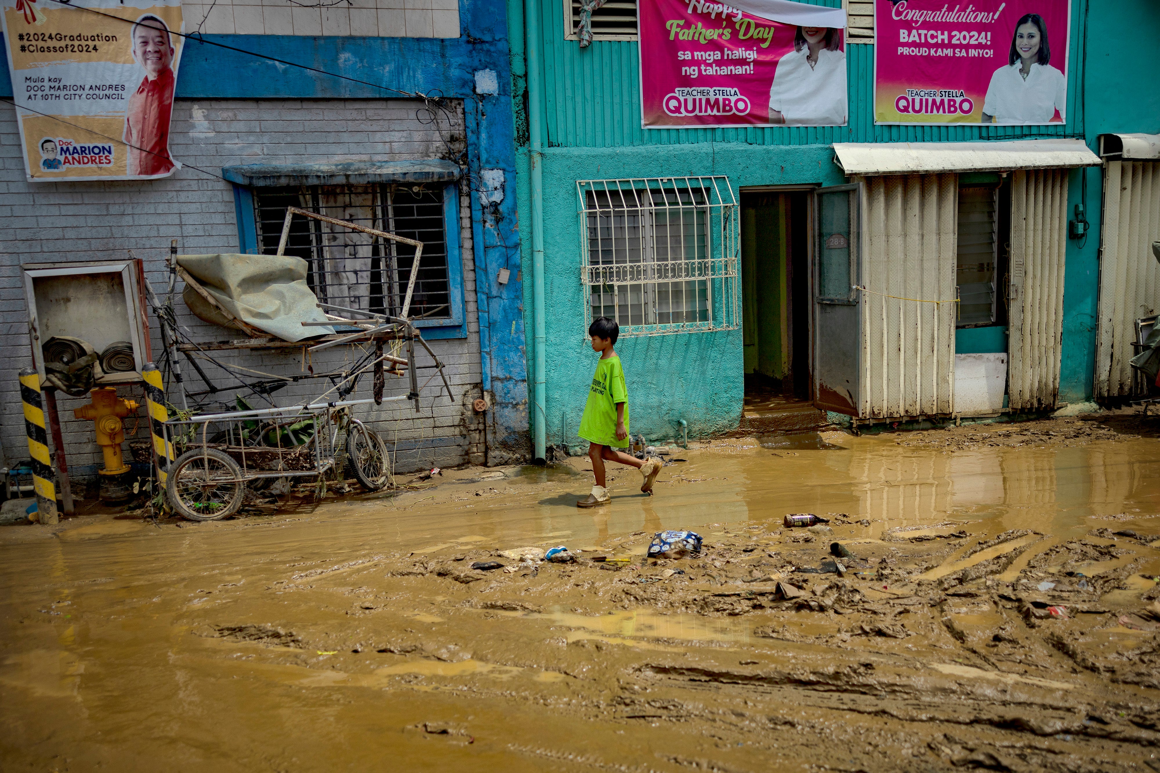 A child walks along a muddied road after it was flooded by rain brought by Gaemi