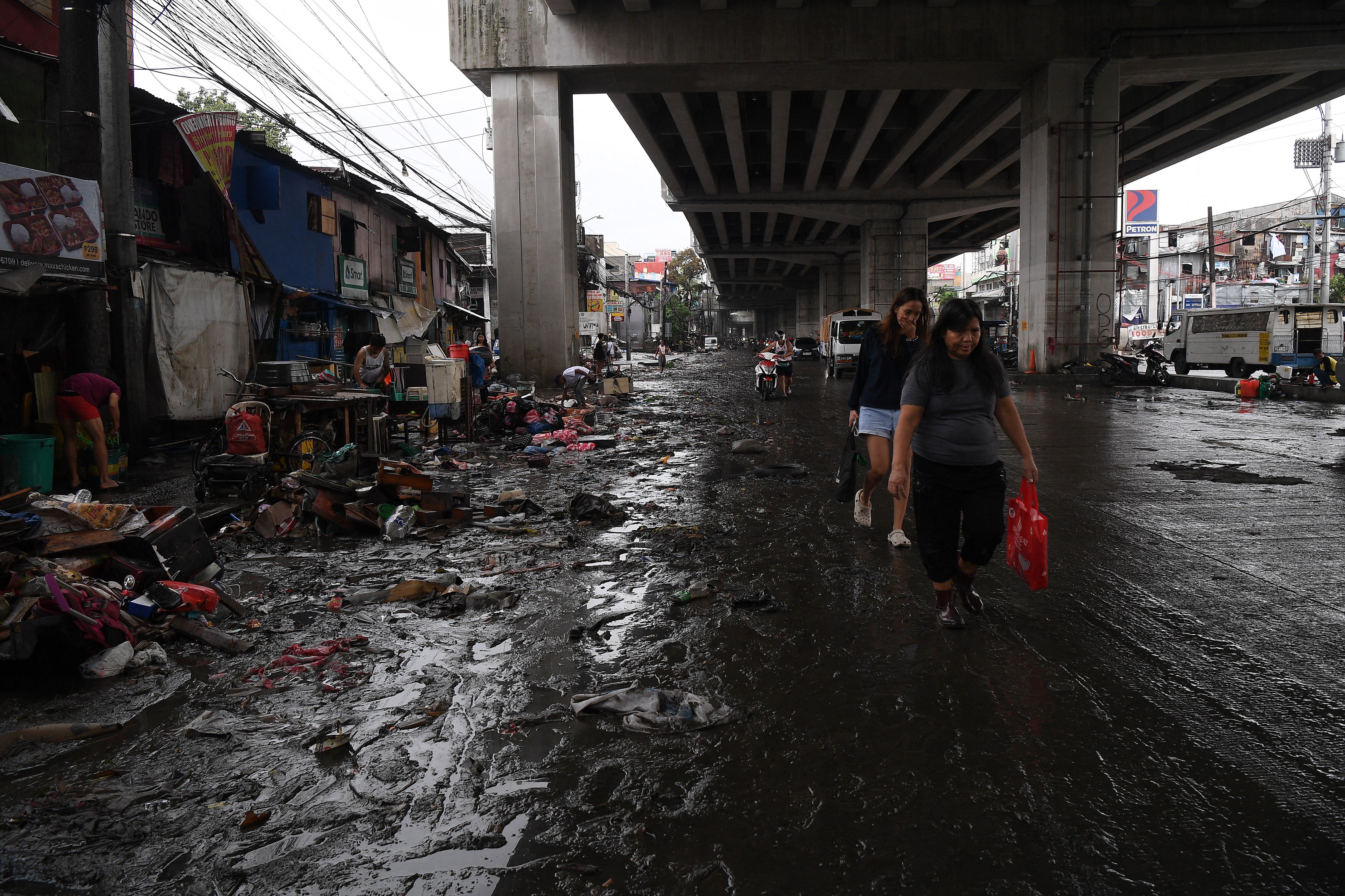 Residents walk along a mudded road caused by floodings in Manila