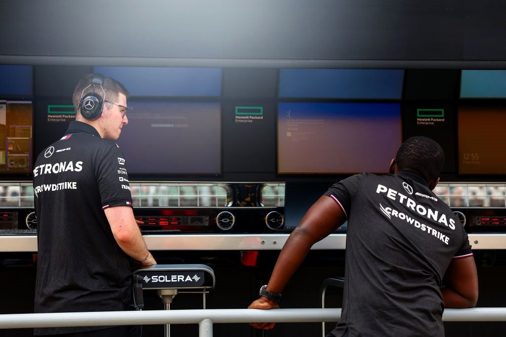 A Mercedes team member, whose shirt bears the logo of team sponsor Crowdstrike, looks on as Windows error screens are seen on their pitwall at the F1 Grand Prix of Hungary on 19 July, 2024 in Budapest, Hungary