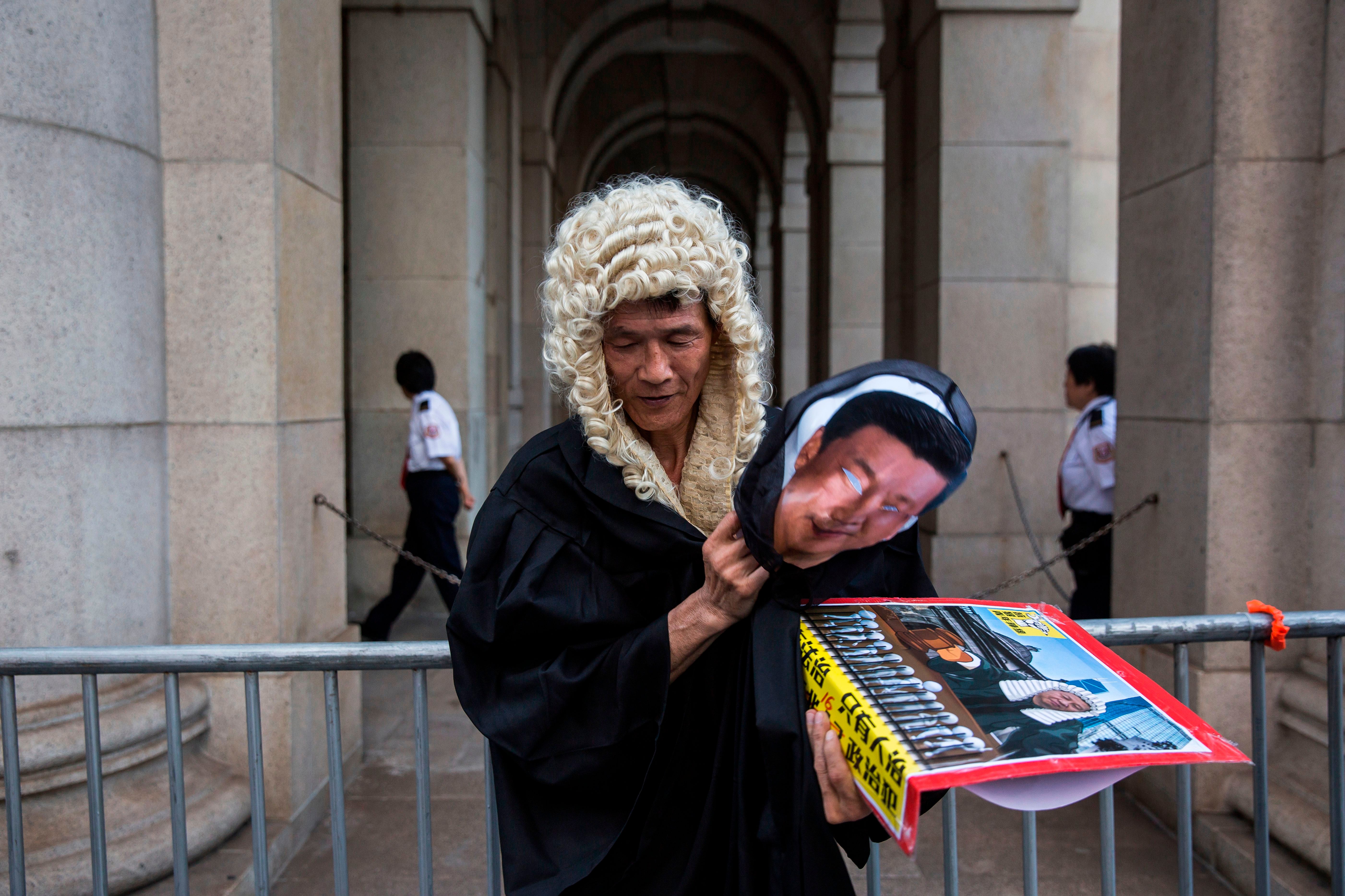 A protester dressed as a judge and carrying a mask of Chinese president Xi Jinping stands outside a court in Hong Kong