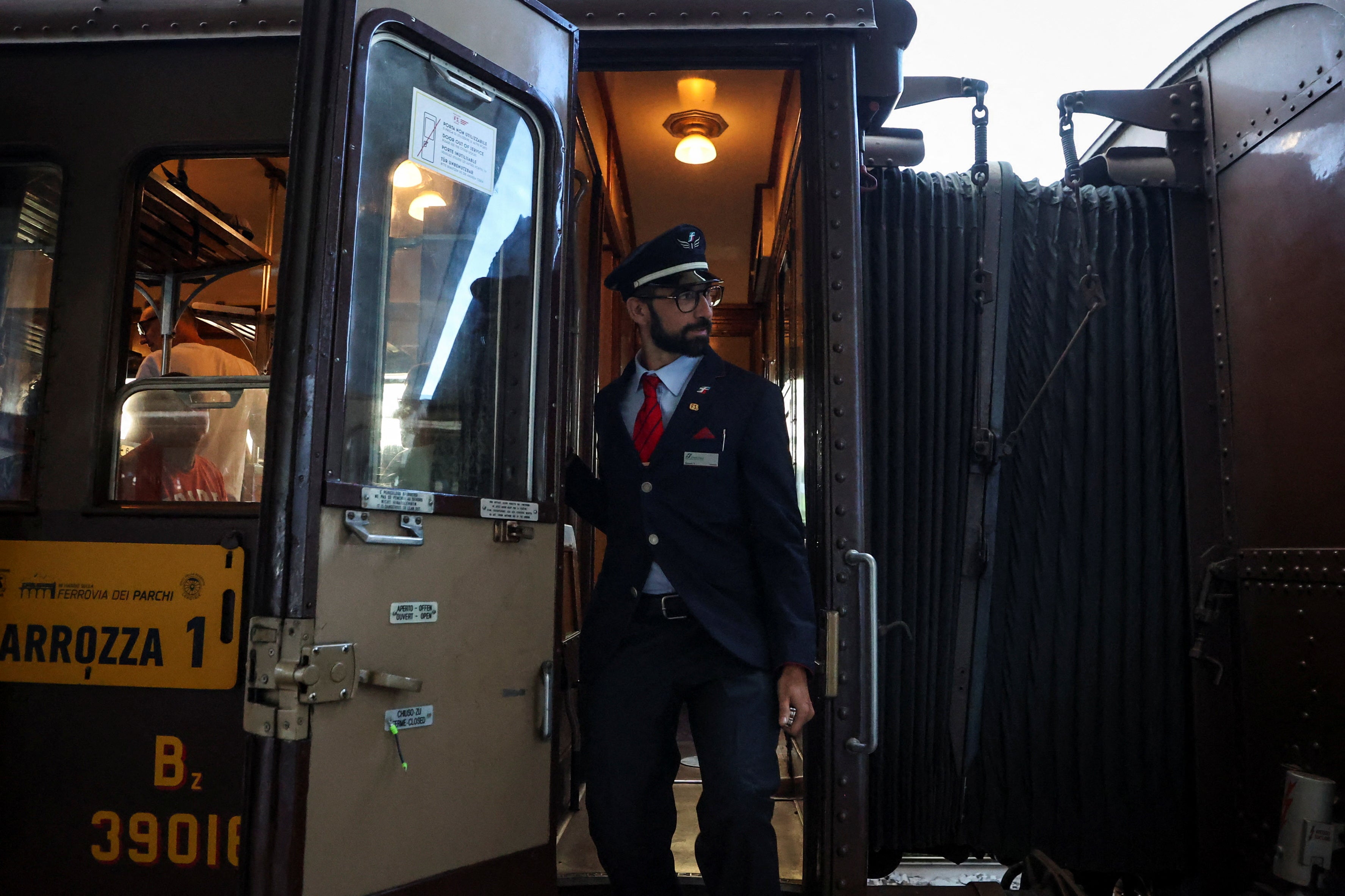 The conductor stands by the door of a vintage carriage at the railway station in Sulmona