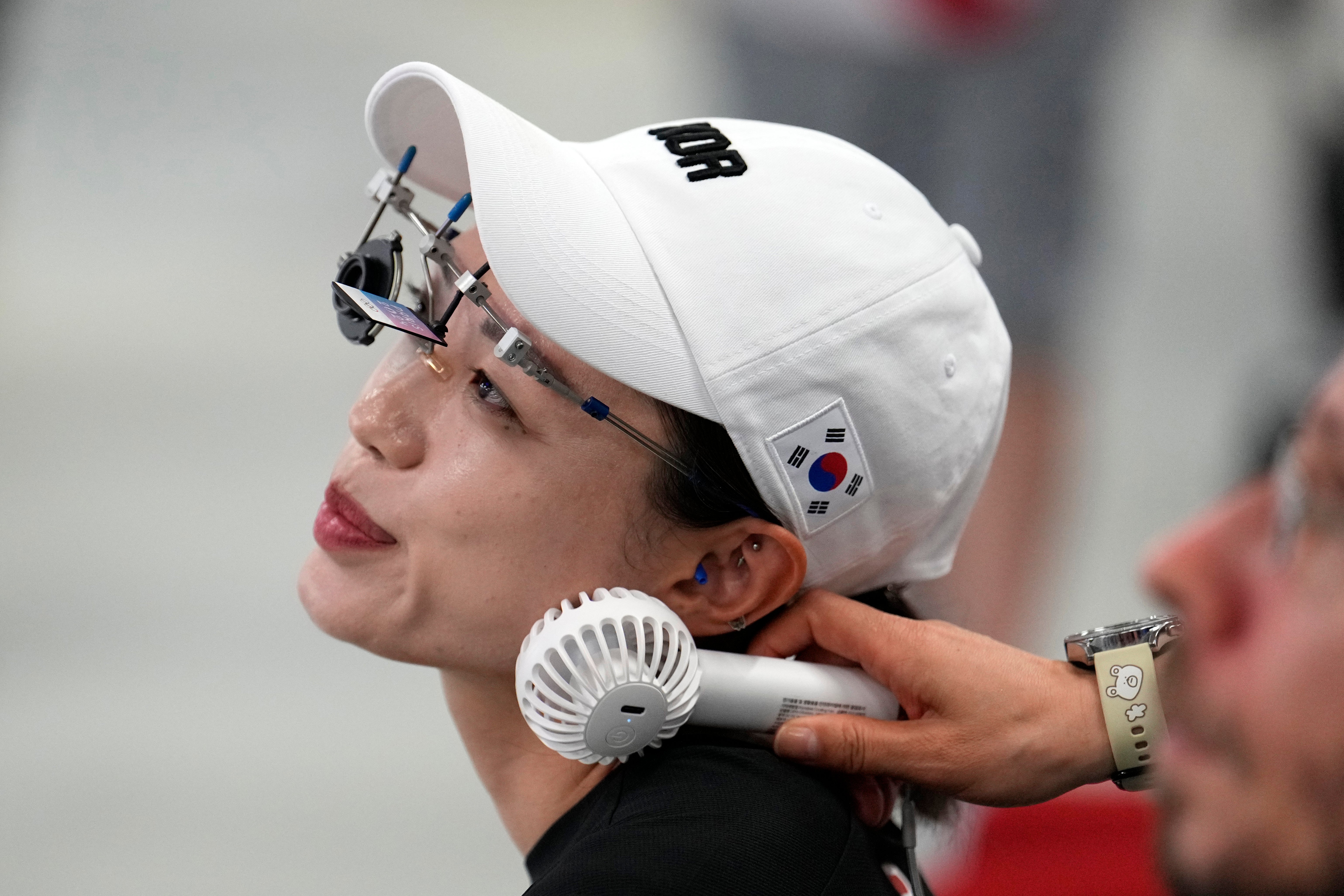 Kim Ye-ji receives a blast of air from a portable fan during the 10m air pistol women's qualification round at the Olympics