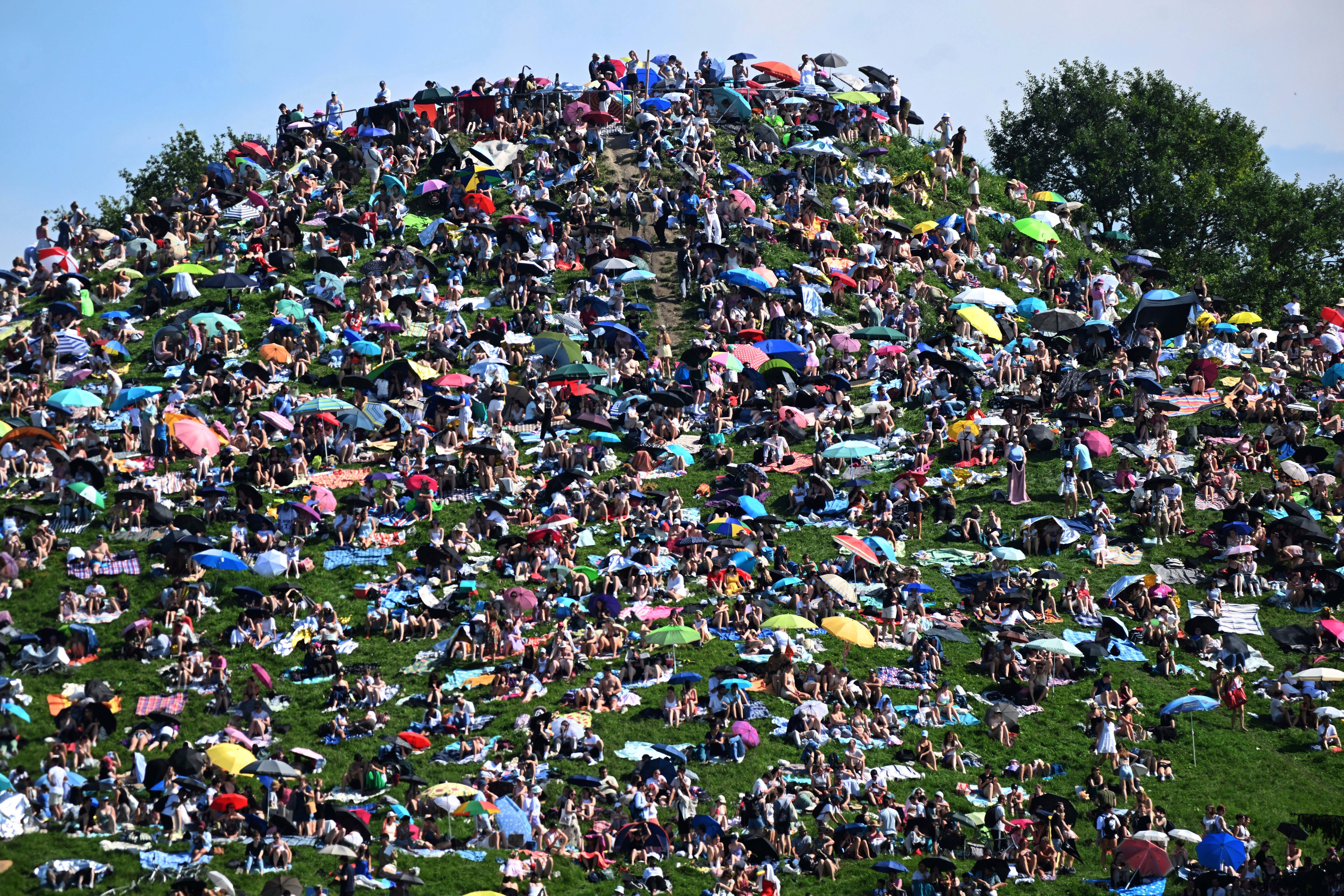 Fans sit on the Olympiaberg and wait in the sunshine for the Taylor Swift concert to begin, in Munich, Germany