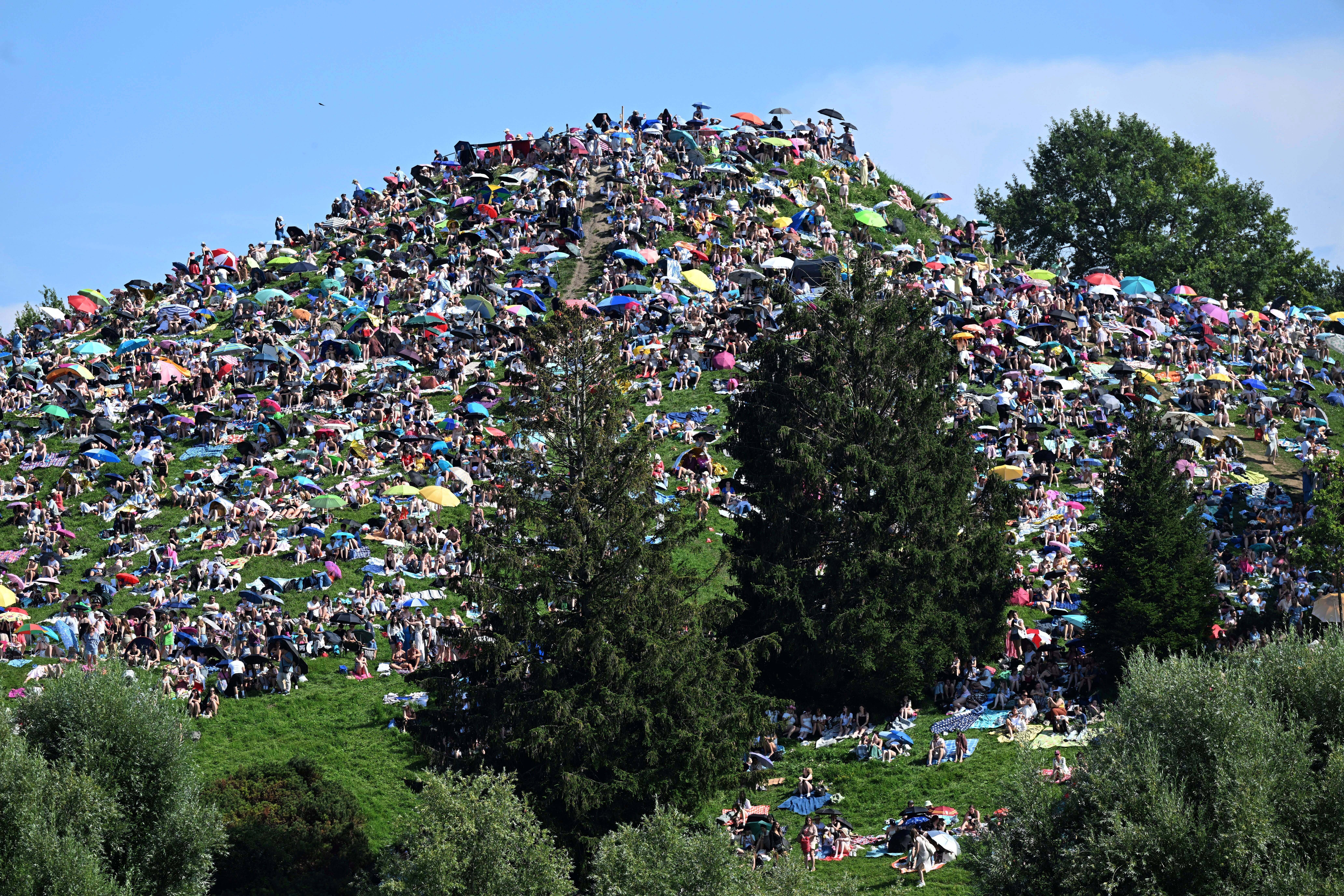 Fans sit on the Olympiaberg and wait in the sunshine for the Taylor Swift concert to begin, in Munich, Germany