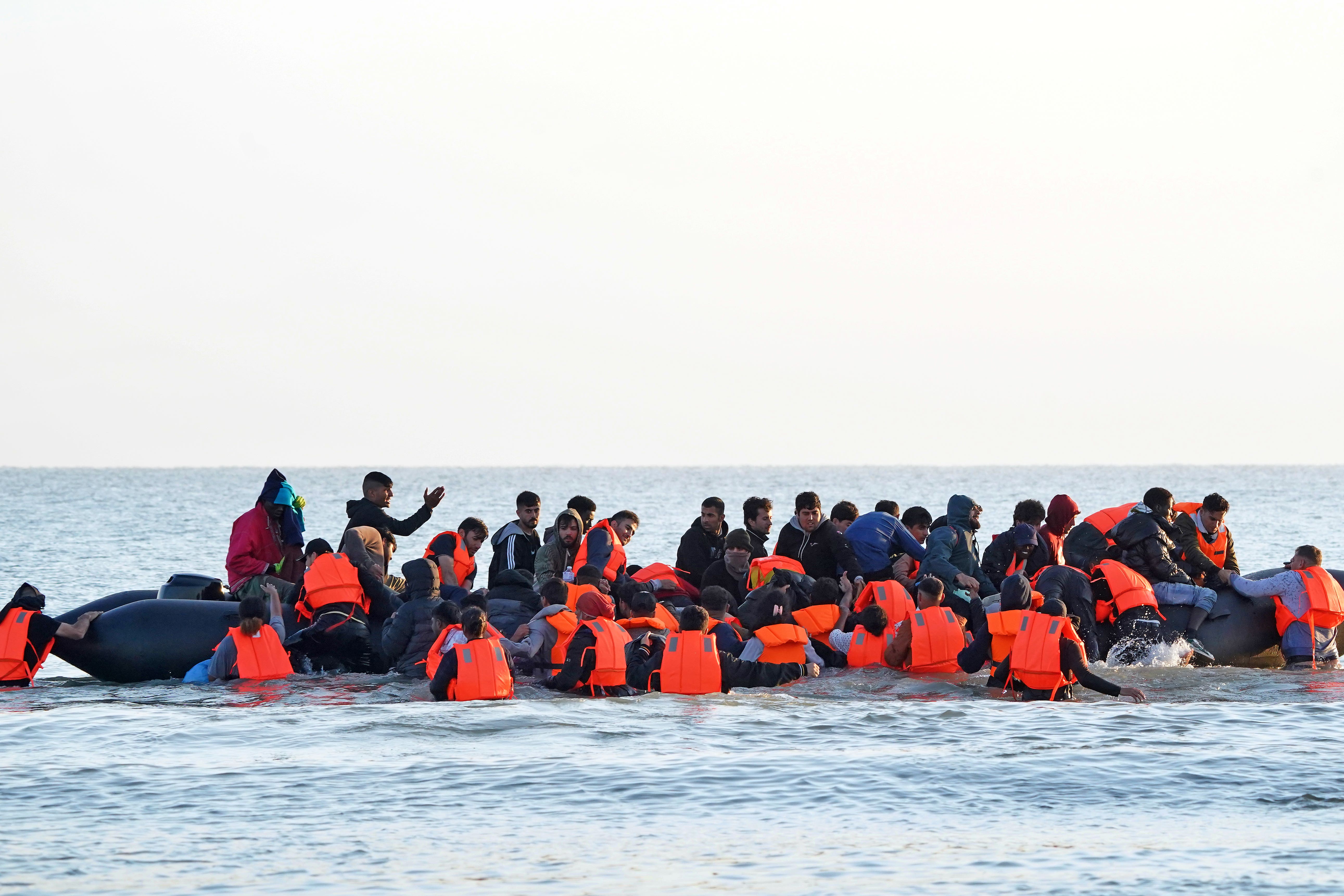 A group of people thought to be migrants wade through the sea to clamber aboard a small boat off the beach in Gravelines, France (Gareth Fuller/PA)