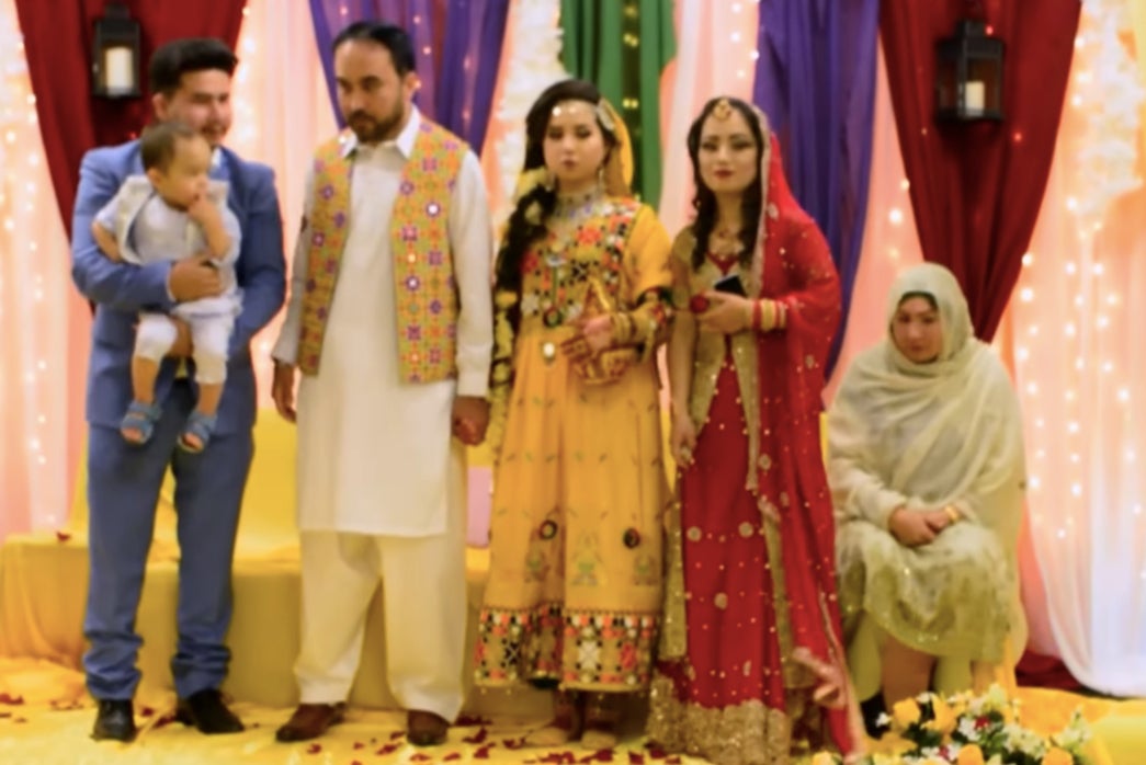 Ruqia Haidari, 21, (in centre in a yellow dress) stands with her husband Mohammad Ali Halimi on her right during their wedding