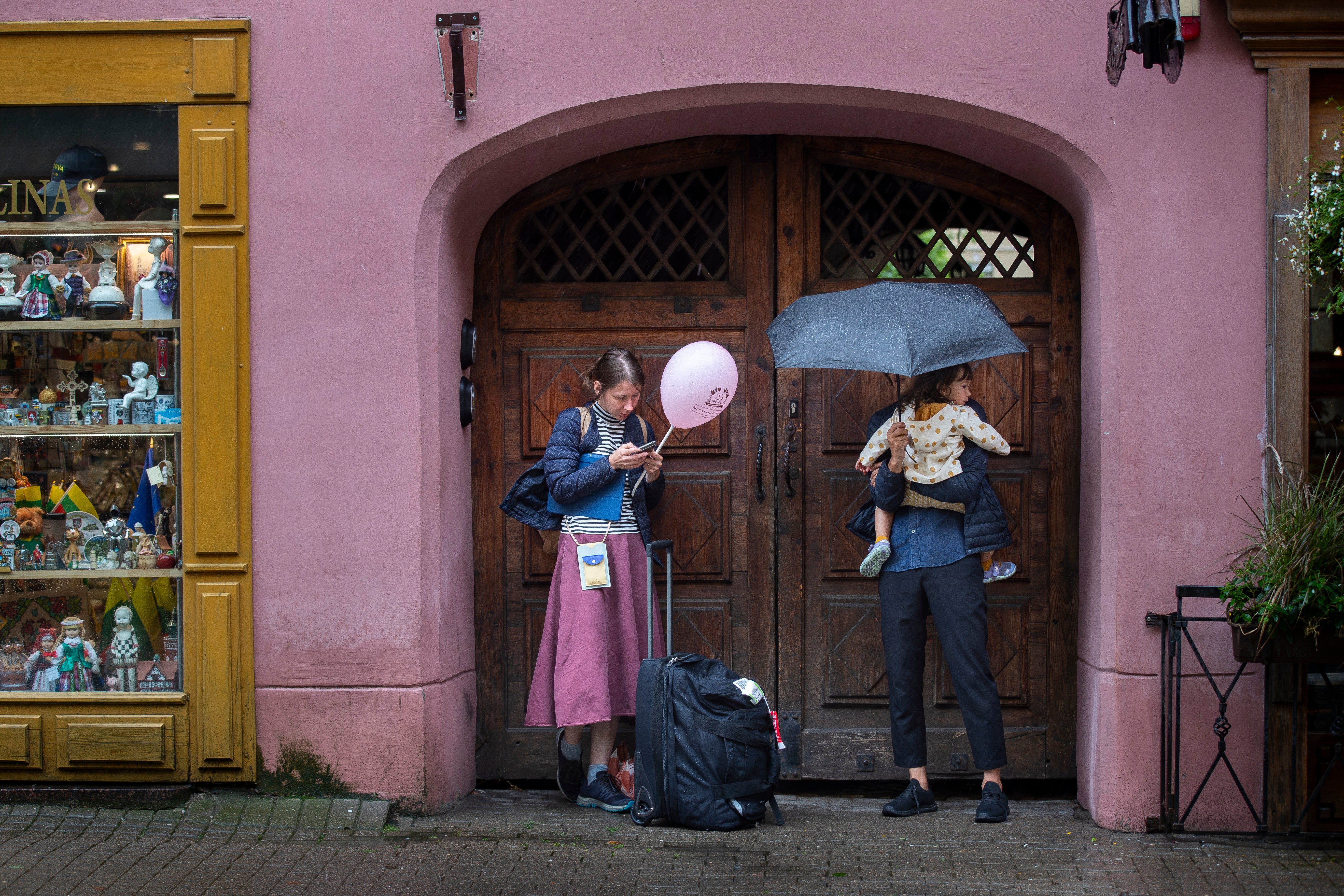 People shelter from the rain in Vilnius, Lithuania, Monday, July 29, 2024