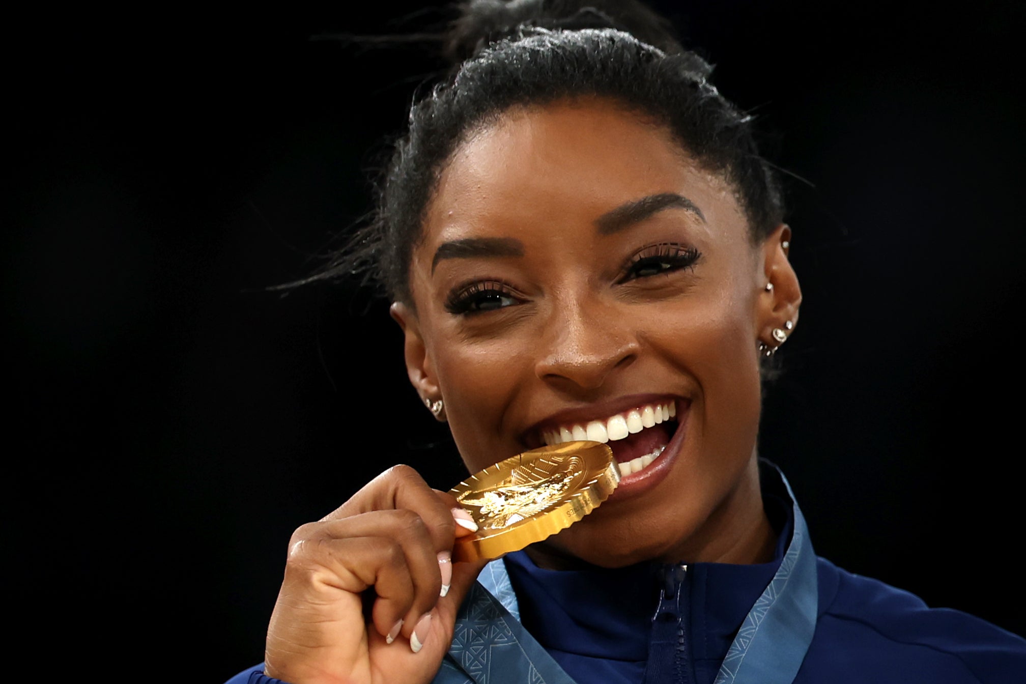 Simone Biles celebrates in traditional style with the medal bite