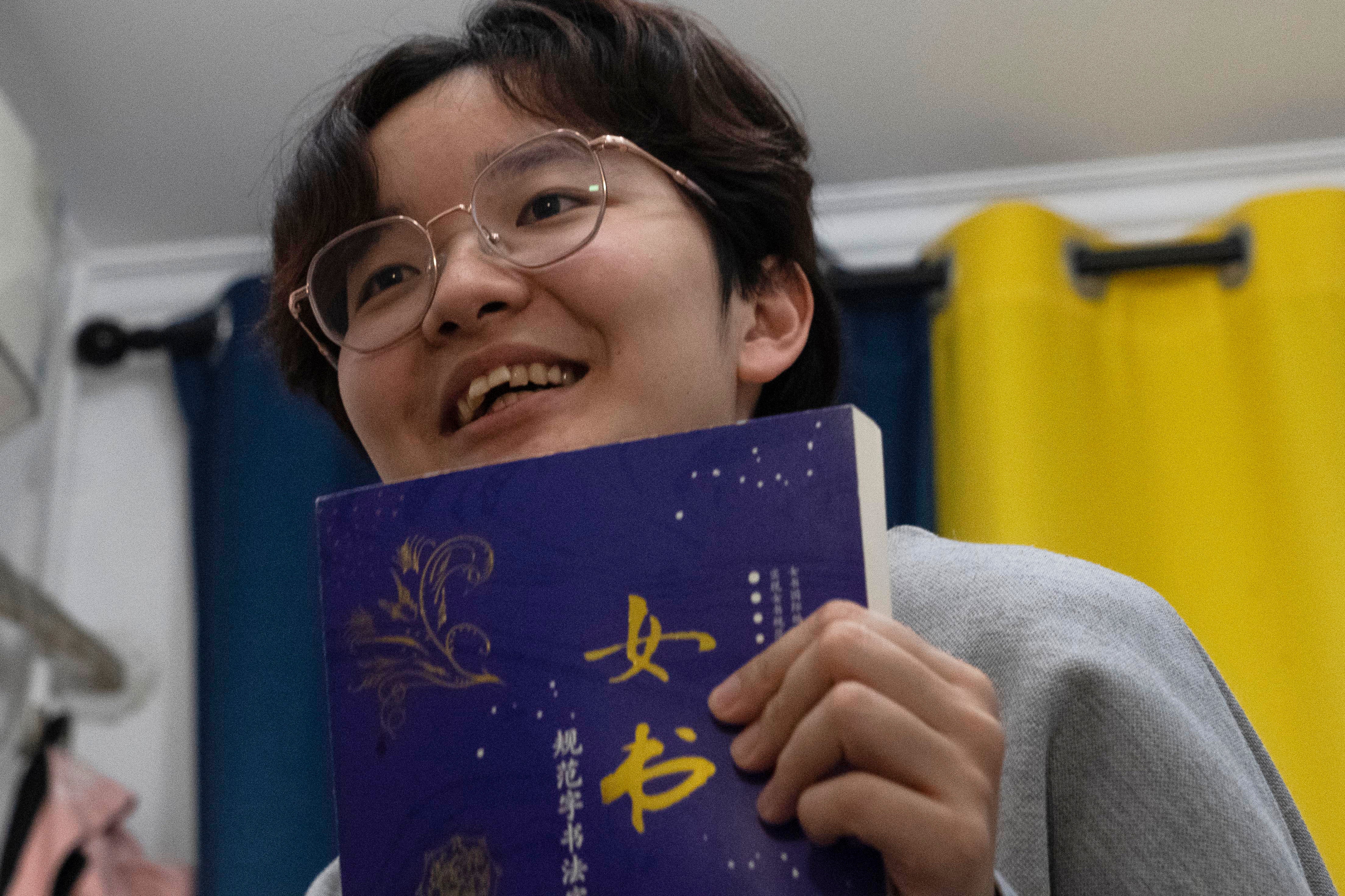 Lu Sirui, a 24-year-old working as a marketer, holds up a book with the word for nüshu