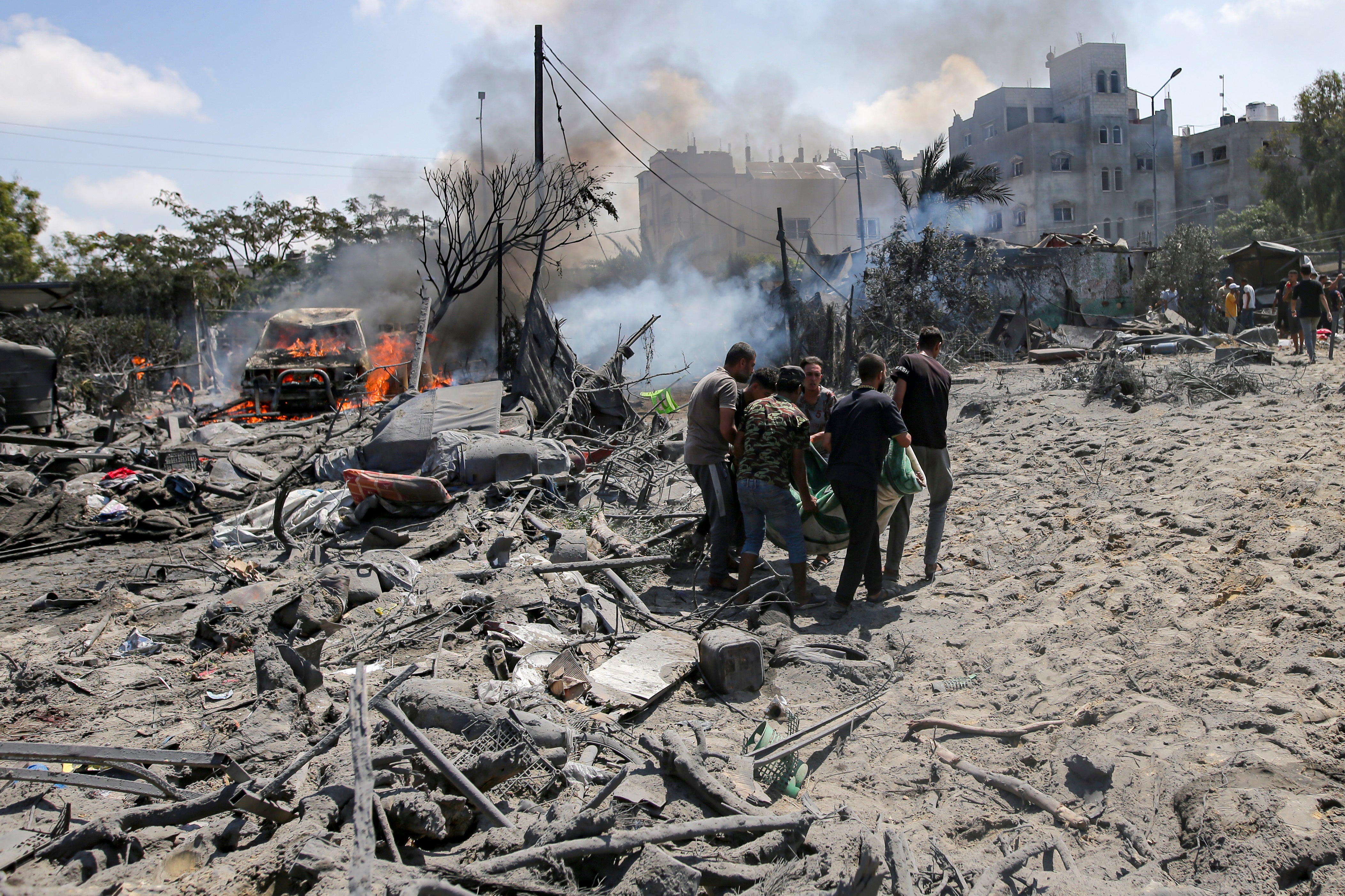 Palestinians evacuate a body from a site hit by an Israeli bombardment on Khan Younis, southern Gaza Strip