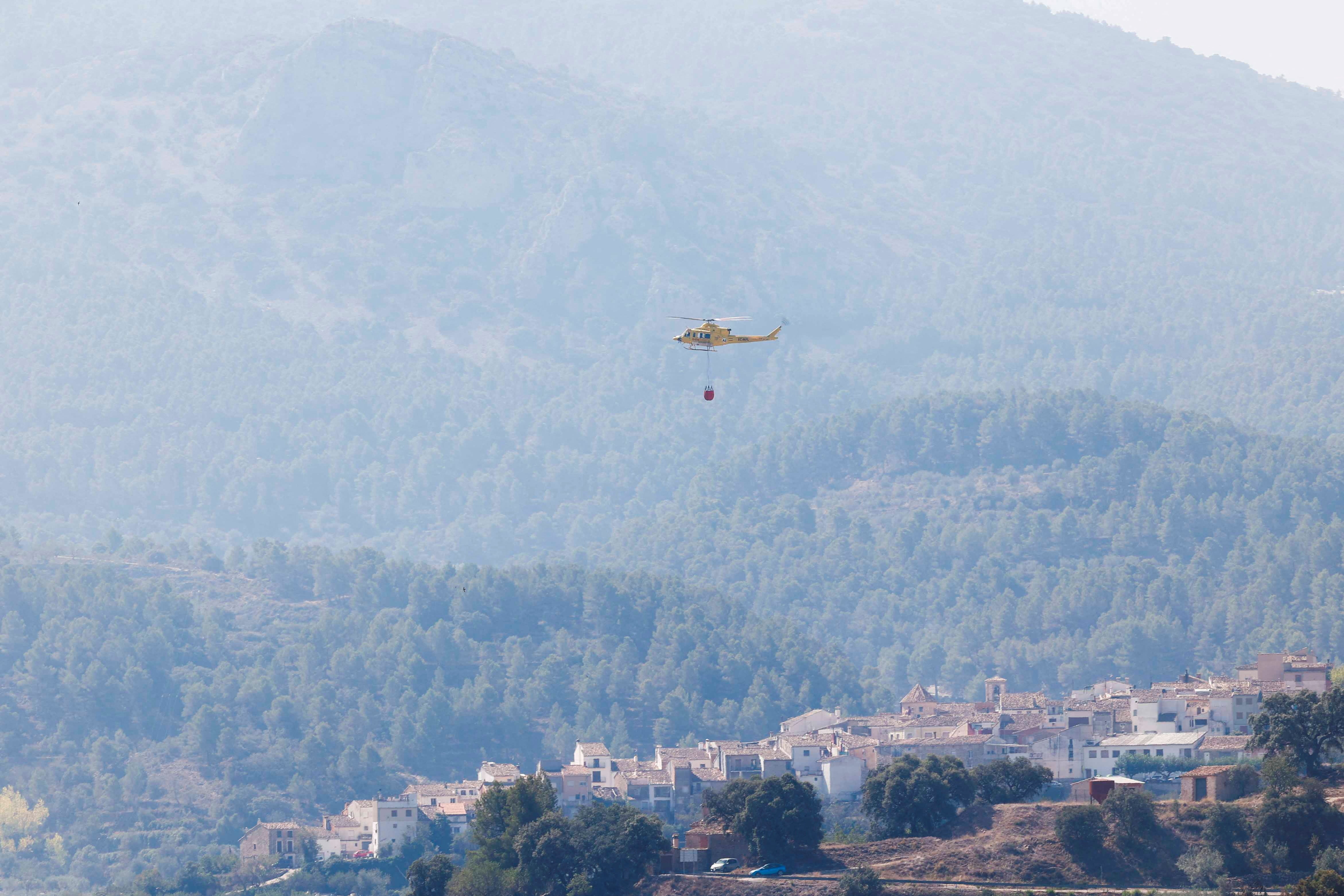 A view of a helicopter as emergency personnel work to extinguish wildfire, as seen from Benasau, Spain July 31