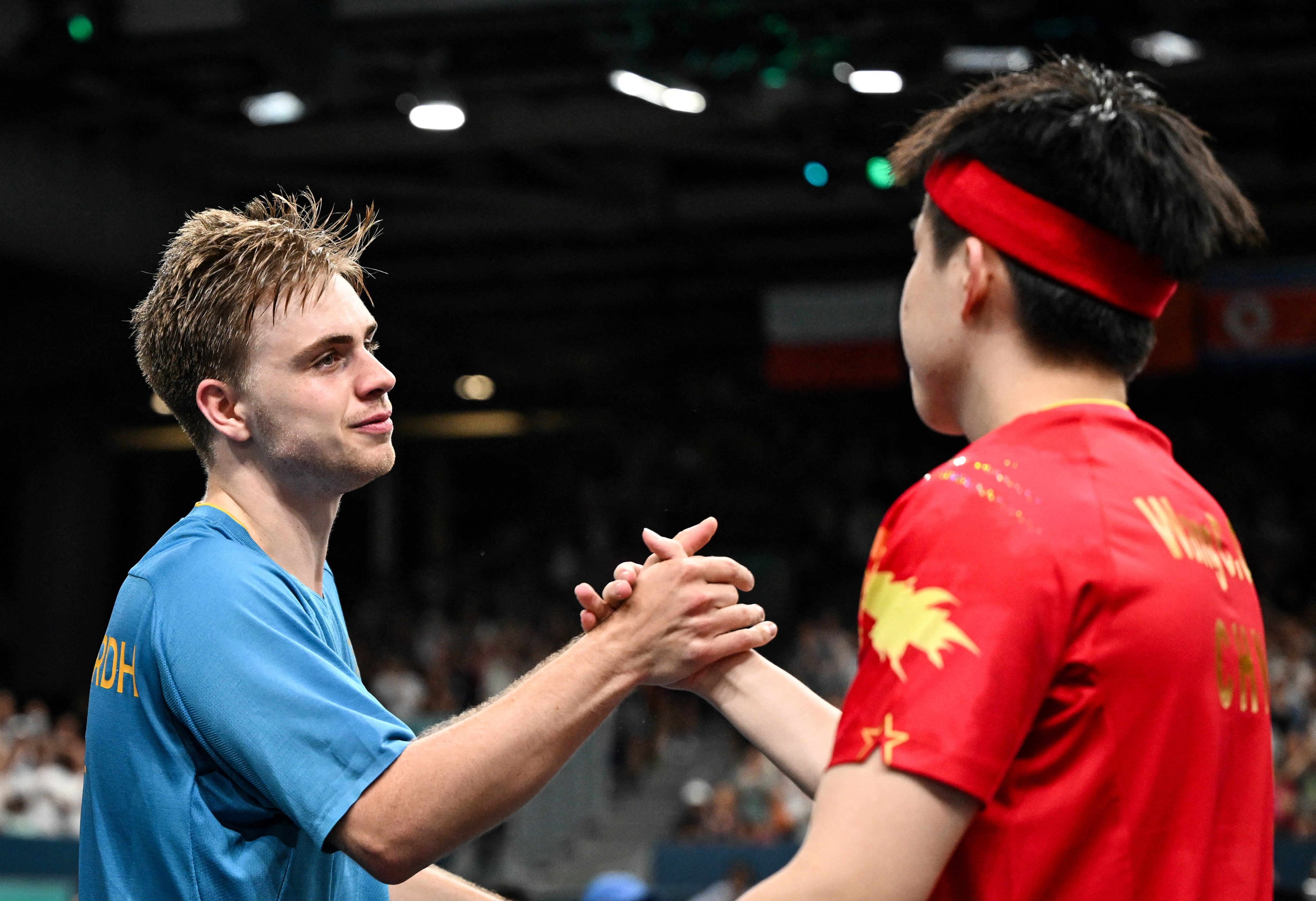 Winner Sweden's Truls Moregard (L) shakes hands with China's Wang Chuqin