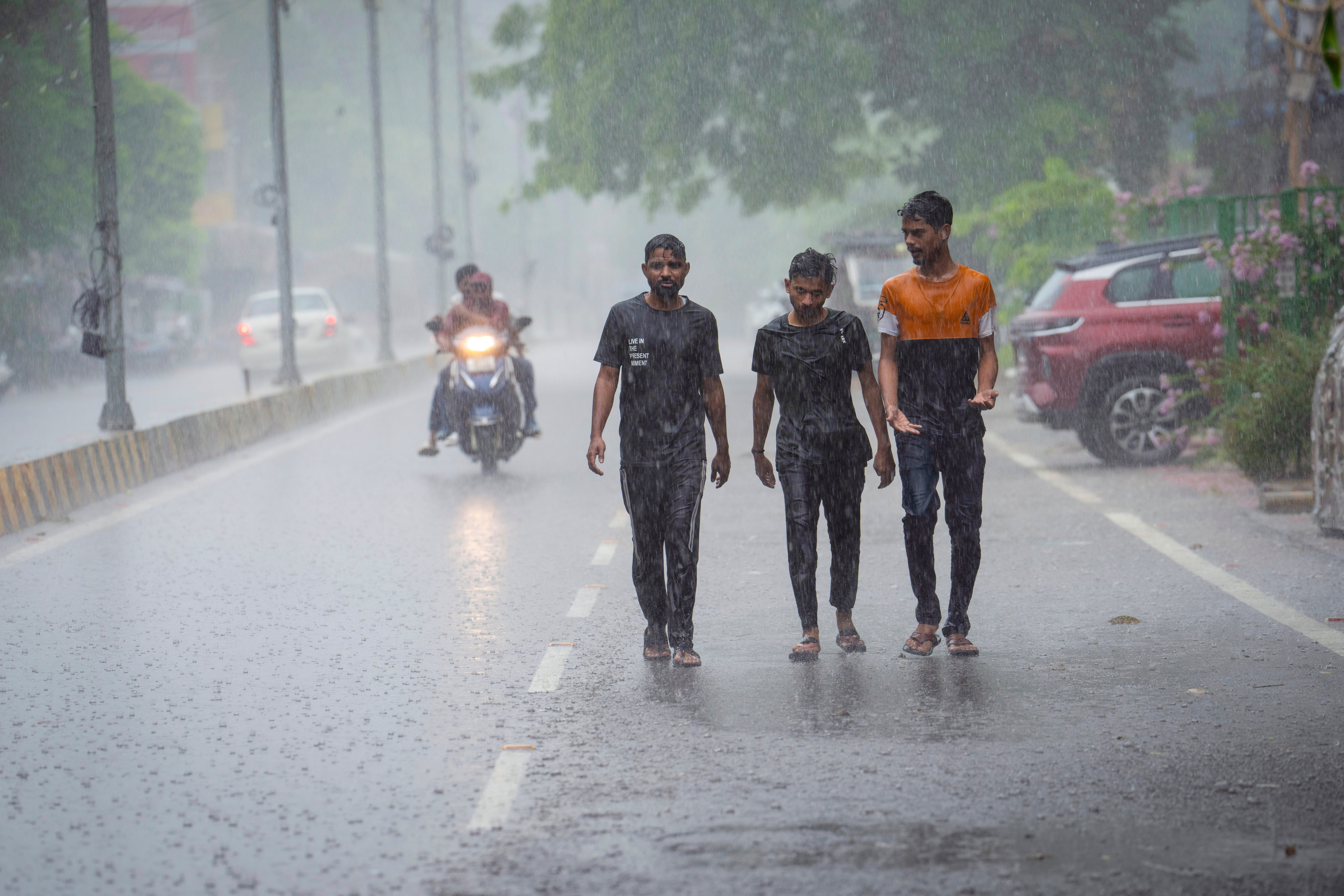 Indian men walk through a road during heavy rain in Prayagraj, in the northern state of Uttar Pradesh, India, Wednesday, 31 July 2024