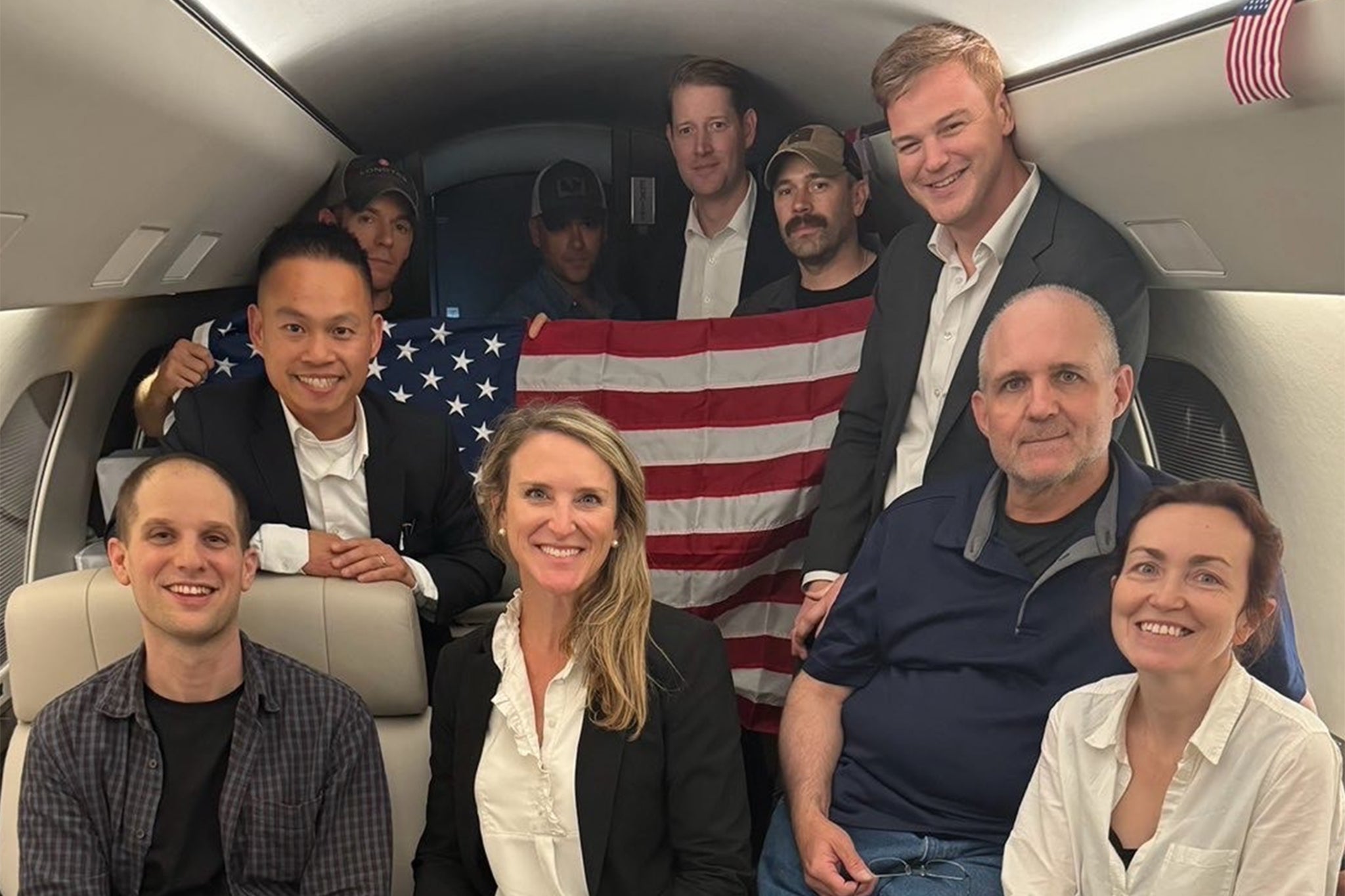 US journalist Evan Gershkovich (left), former US Marine Paul Whelan (second from right) and US-Russian journalist Alsu Kurmasheva (right) are seen on a plane after their release from Russia on August 1