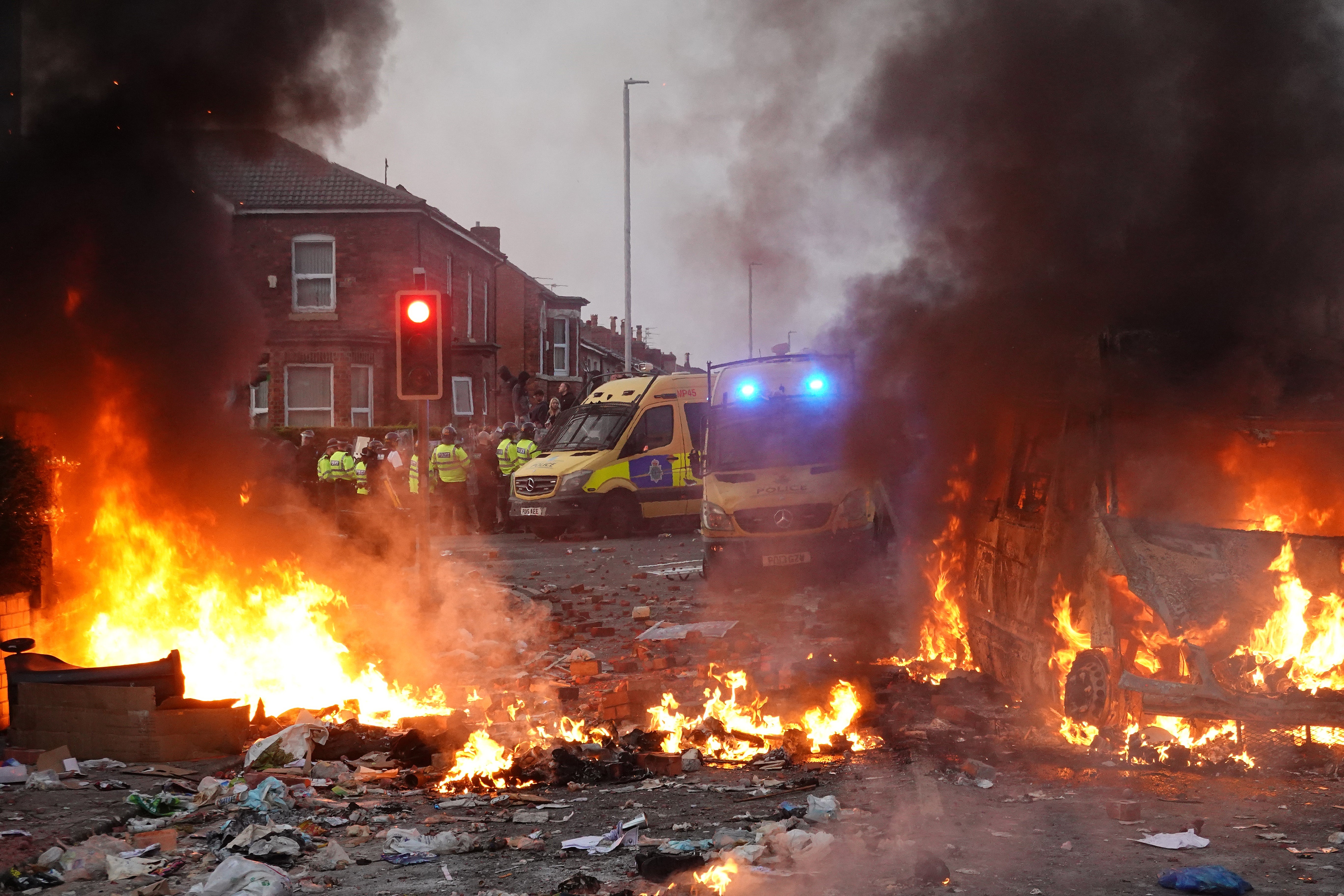 Riot police hold back protesters near a burning police vehicle after disorder broke out on July 30, 2024 in Southport, England. Rumours about the identity of the 17-year-old suspect in yesterday's deadly stabbing attack here have sparked a violent protest.