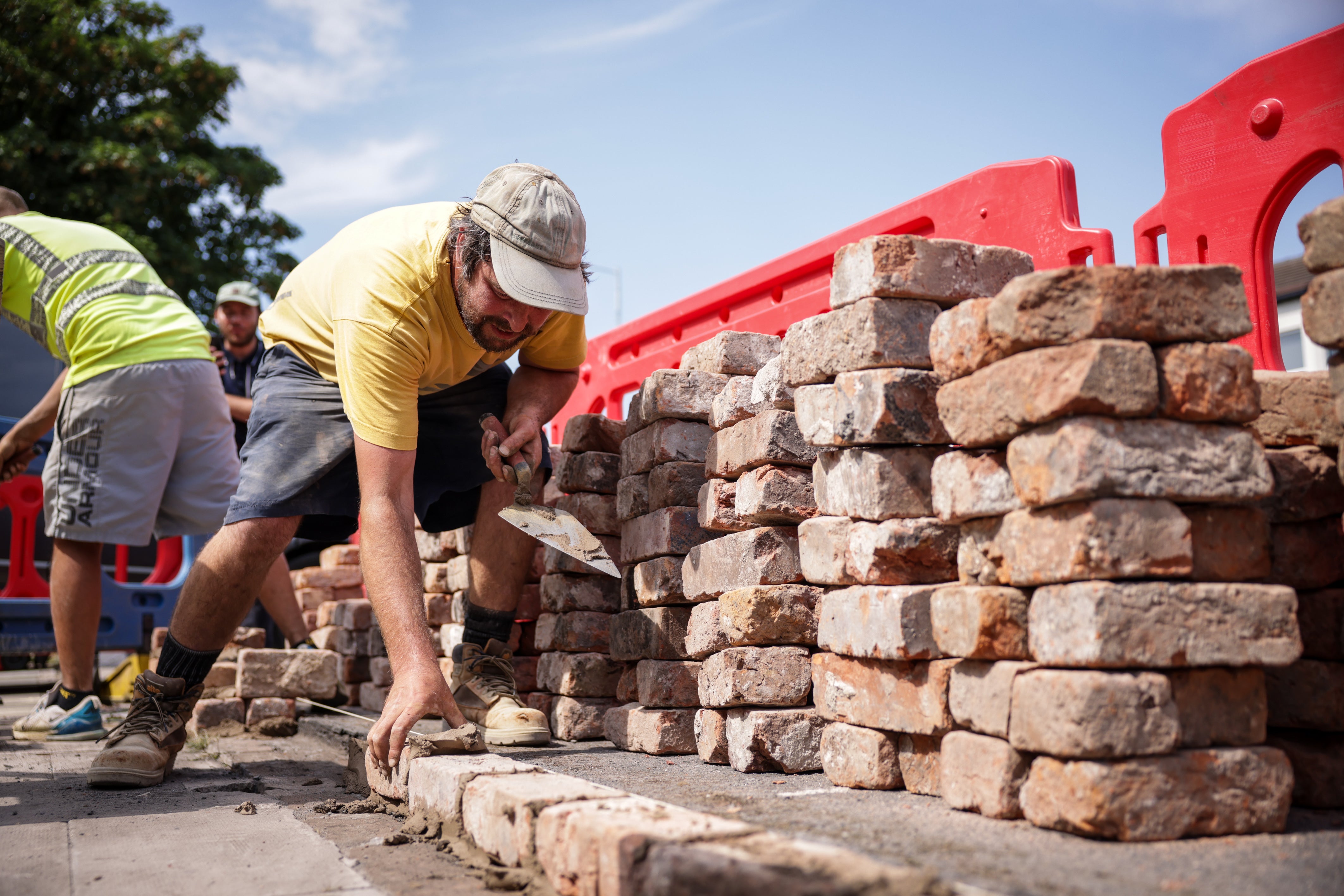 Kingswood Homes workers rebuild a wall outside the Southport Islamic Centre Mosque in Southport, Merseyside, after a protest as police officers suffered serious injuries when bricks, stones and bottles were thrown and cars were set alight during violent protests following a vigil for three girls killed in a knife attack at a Taylor Swift-themed holiday club on Monday.