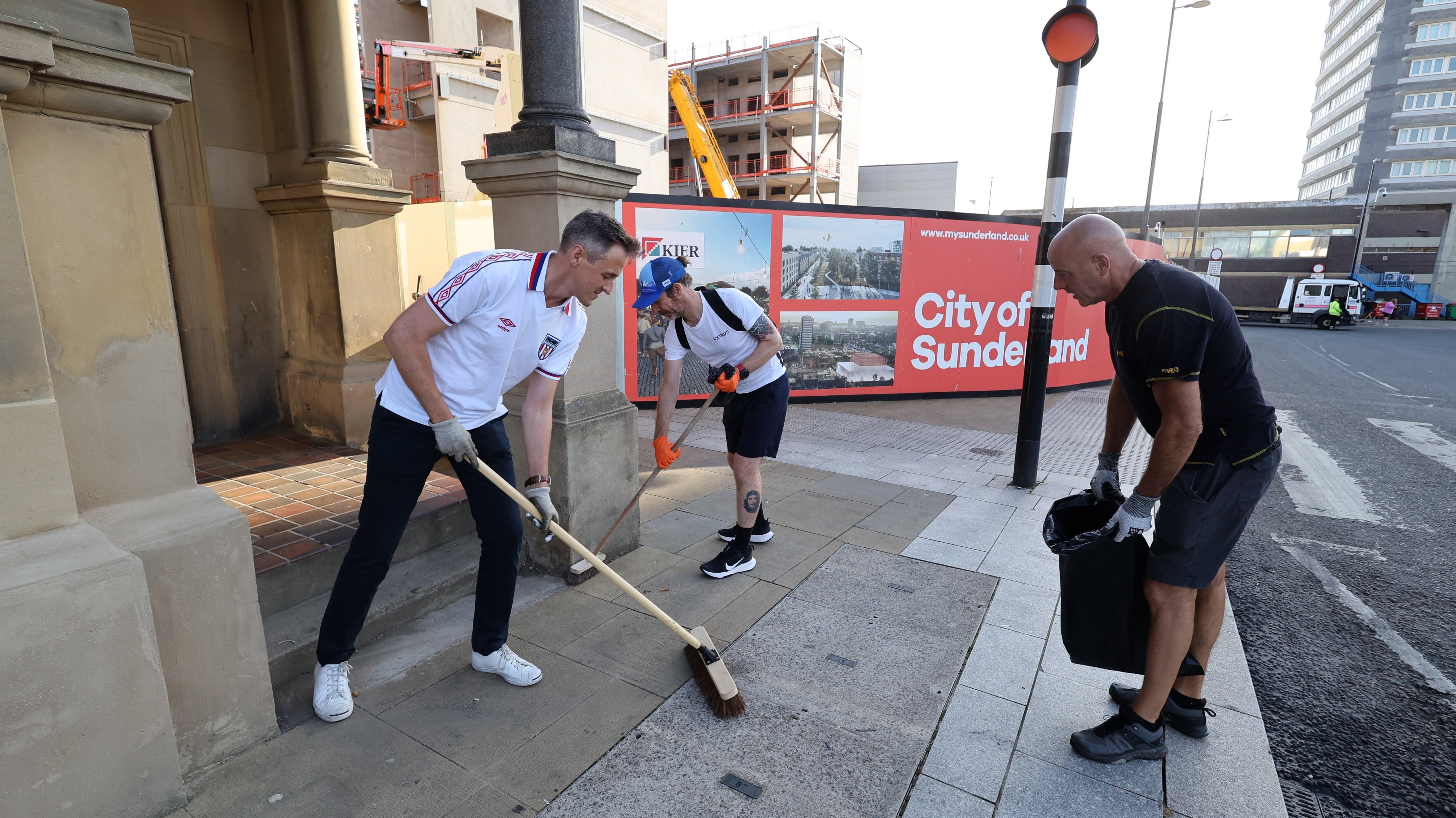 Volunteers with dustpans and broomsticks clearing up debris