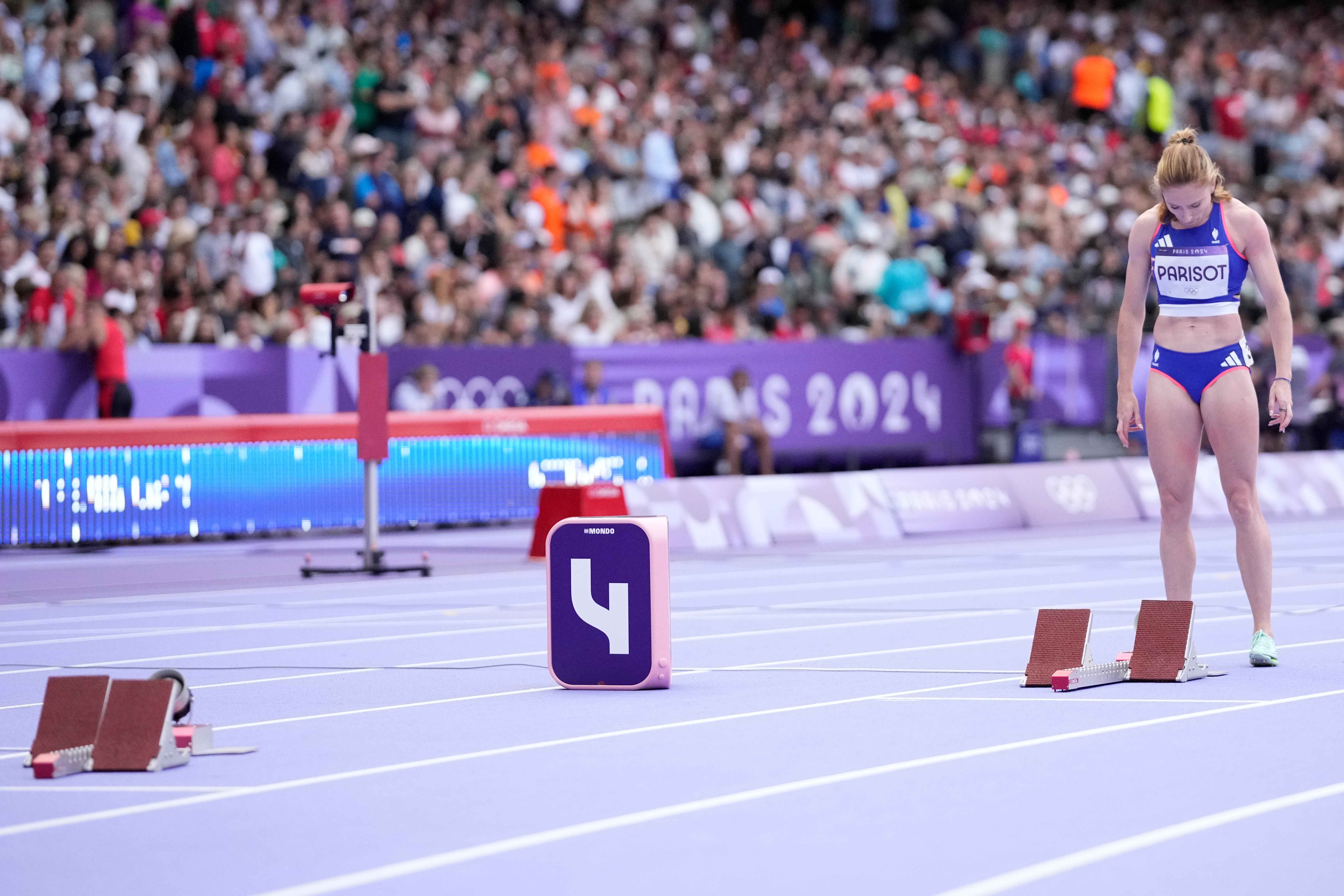 Helene Parisot, of France, stands near the empty start blocks for Shericka Jackson, of Jamaica