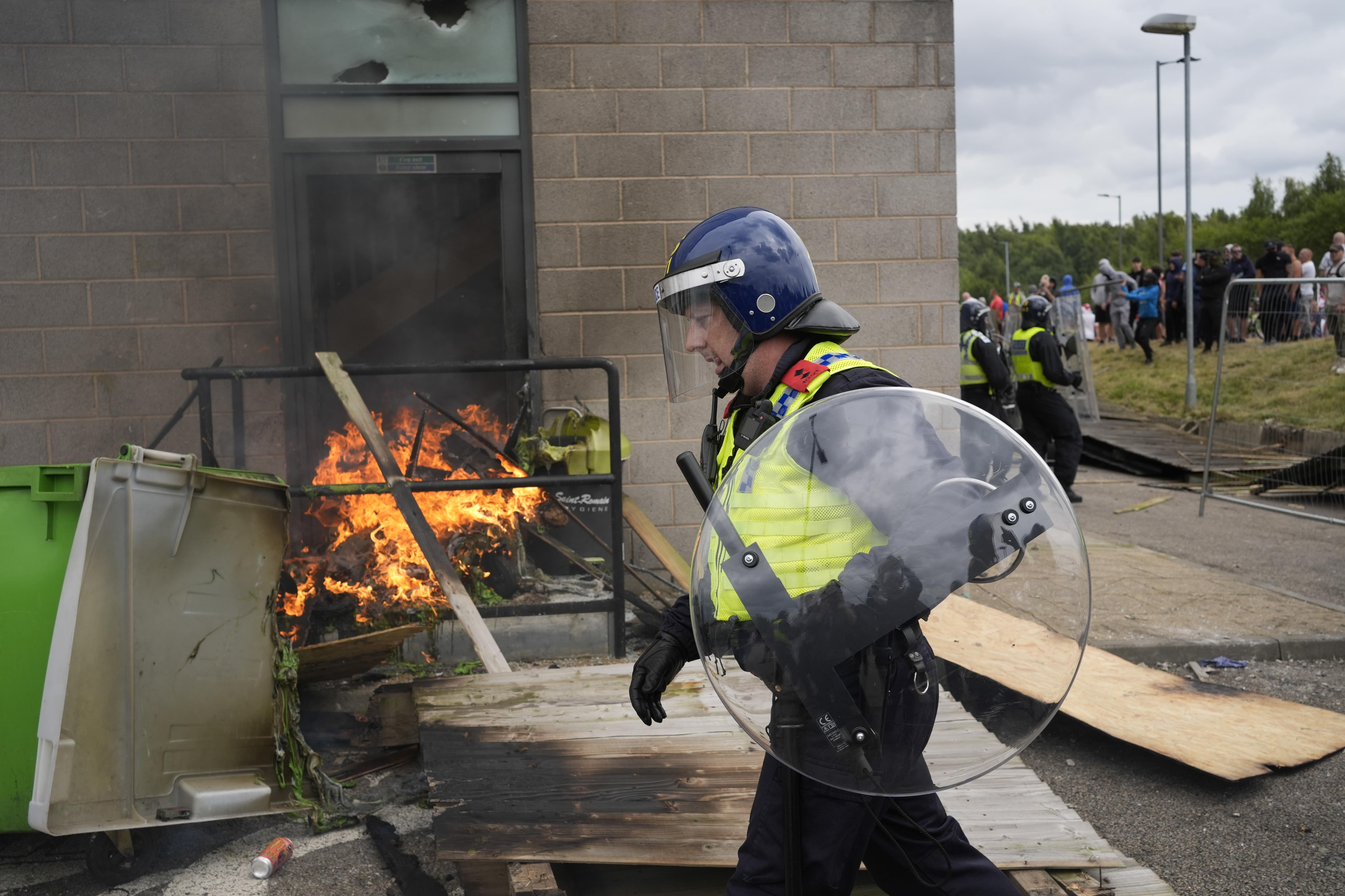 A police officer walks past a fire during clashes between police and rioters in Rotherham