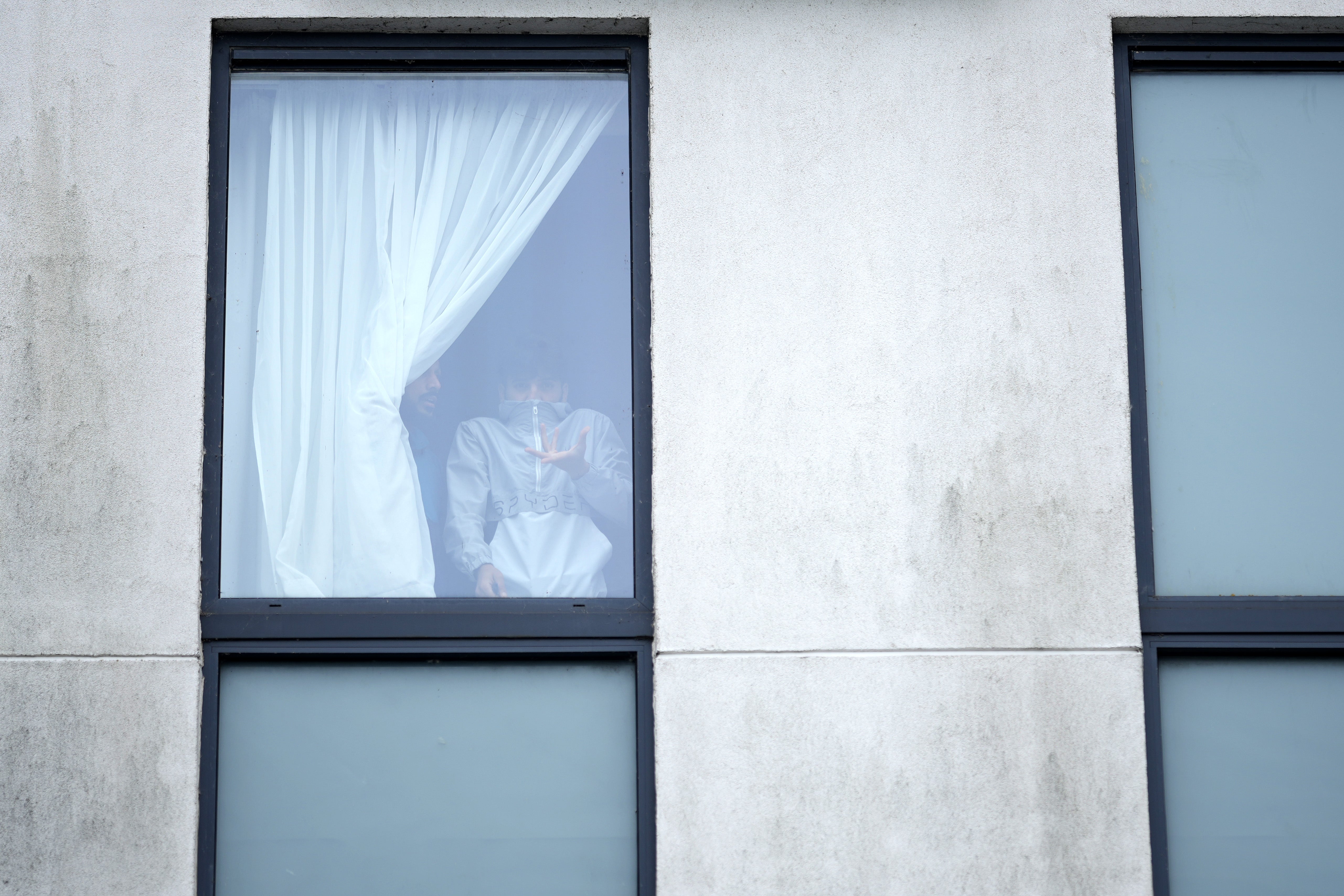 A man looks through a window as rioters attack a hotel housing migrants in Rotherham