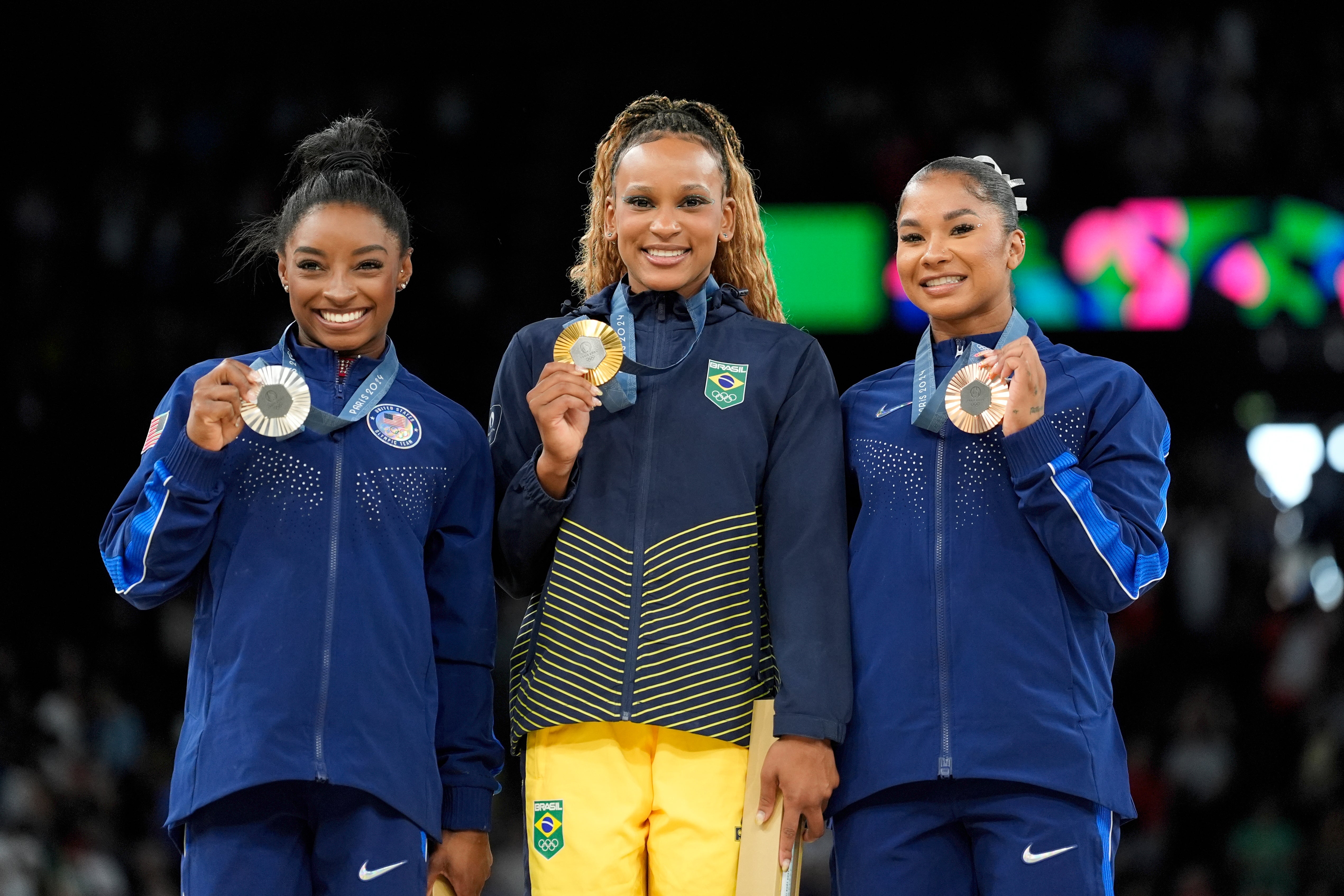 Gold medallist Rebeca Andrade, centre, of Brazil, celebrates on the podium between silver medallist Simone Biles, left, and bronze medallist Jordan Chiles