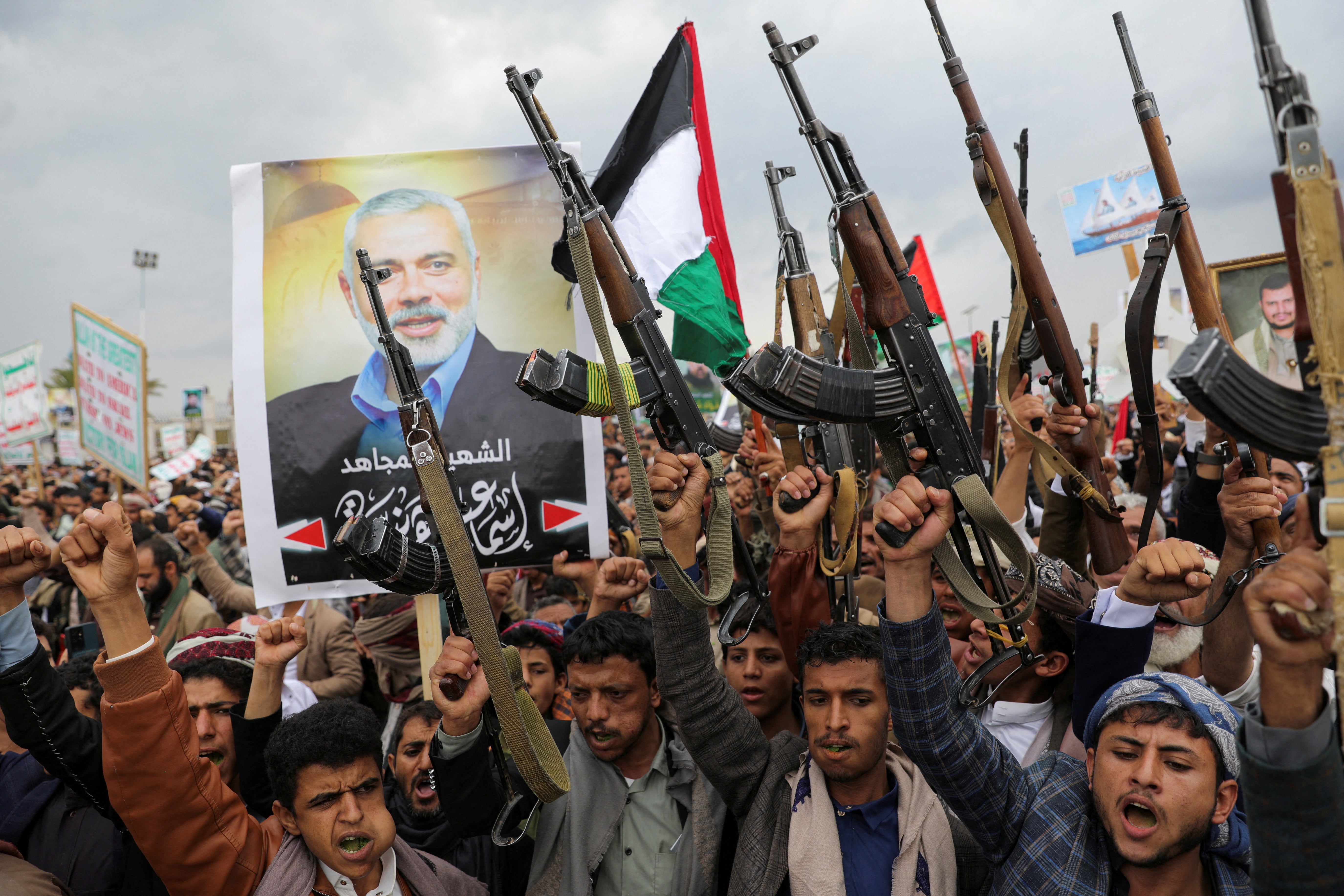 Protesters, mainly Houthi supporters, hold firearms next to a poster of assassinated Hamas chief Ismail Haniyeh, at the rally to show solidarity with Palestinians in the Gaza Strip, in Sanaa, Yemen, 2 August 2024