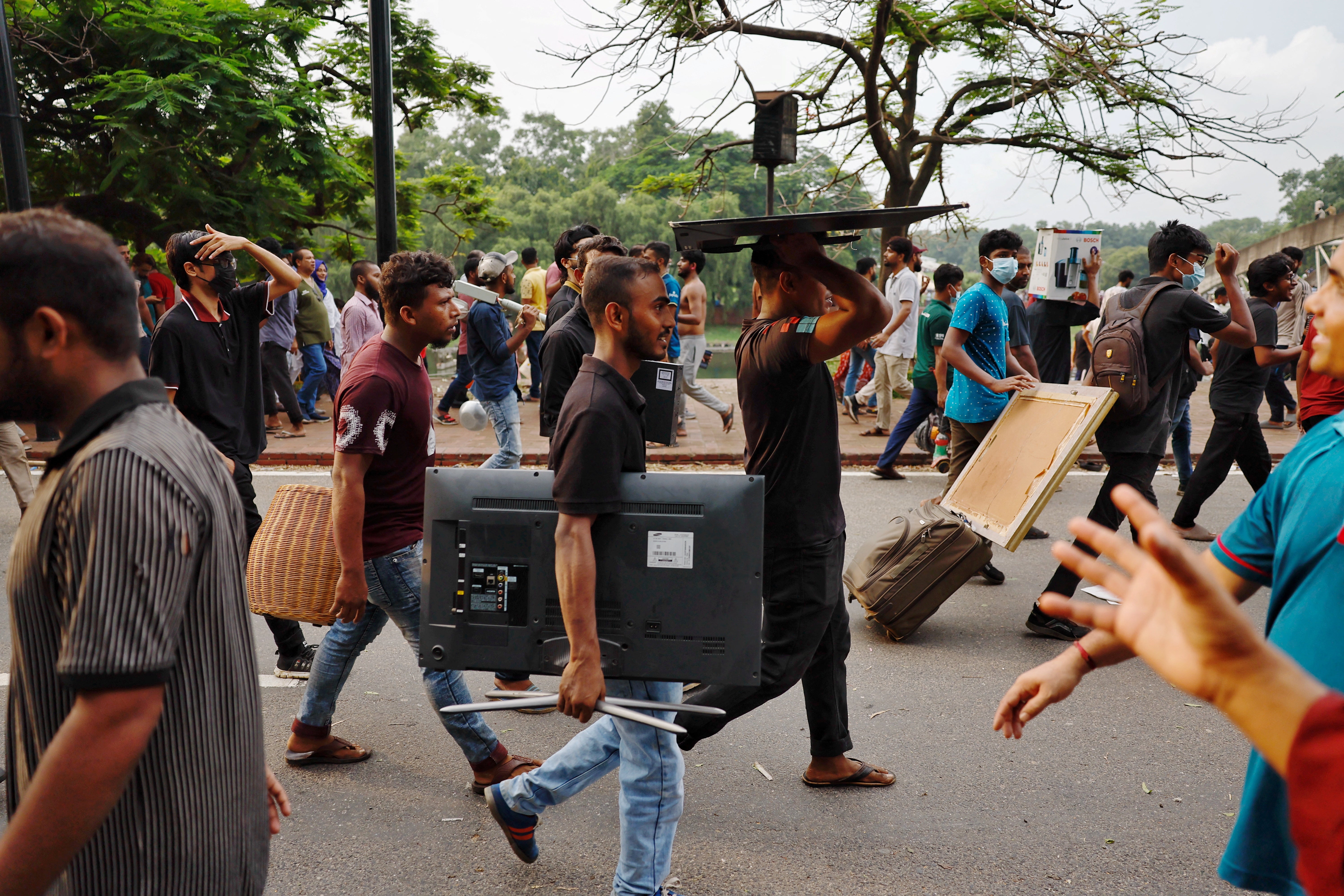 People carry looted items from the Ganabhaban, the prime minister’s residence in Dhaka