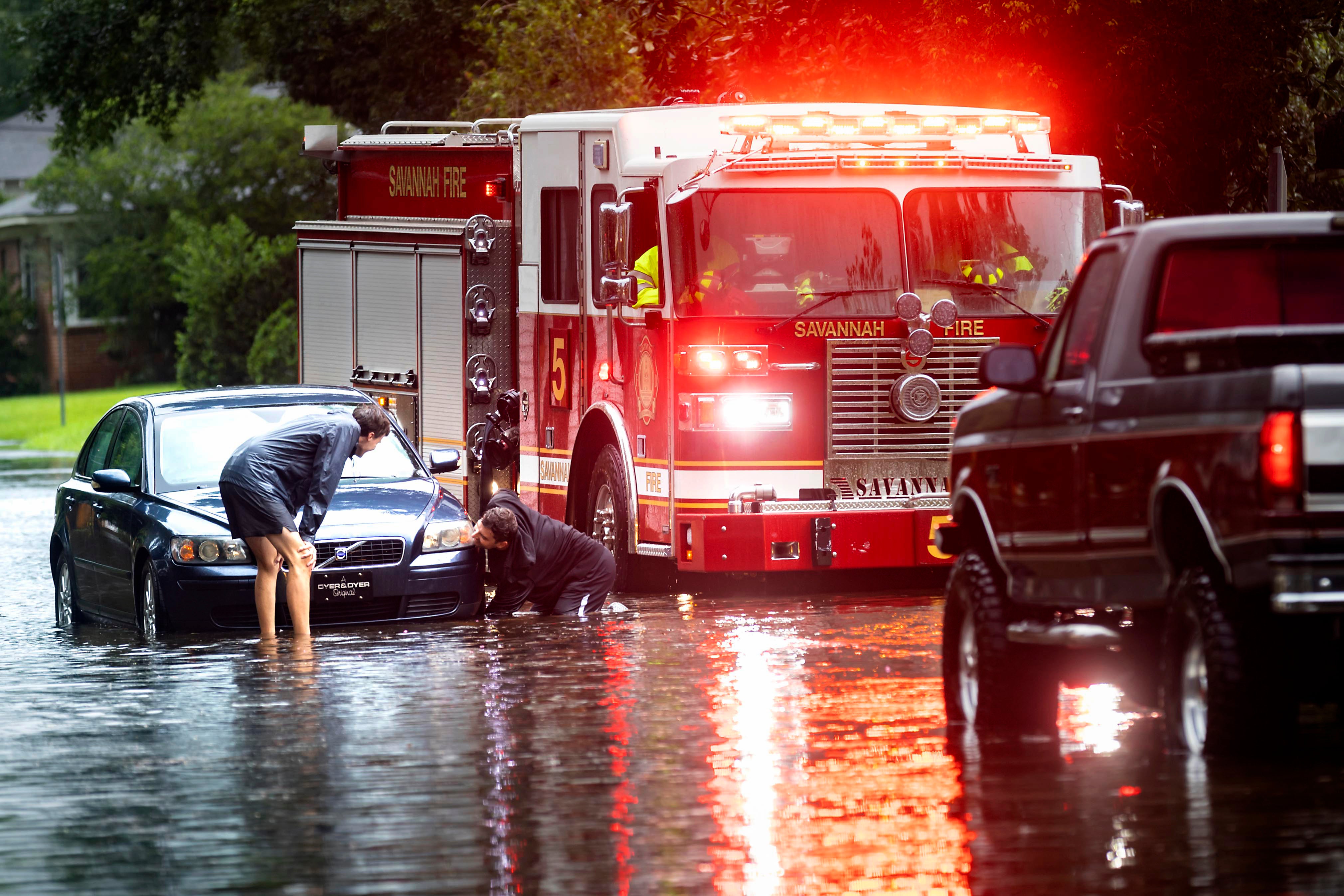 People attach a towline to a stranded vehicle on a flooded street in Savannah, Georgia