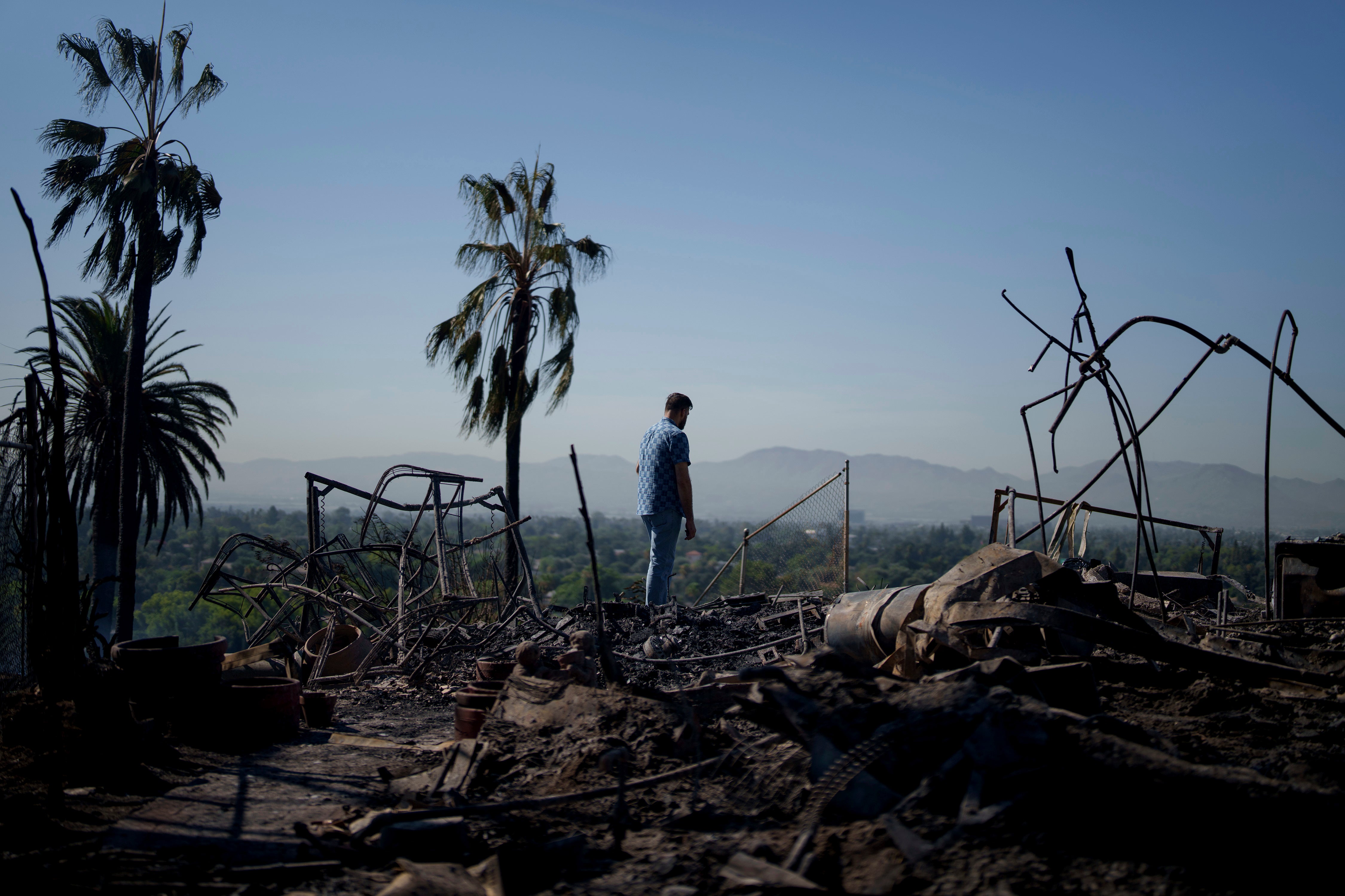 A man looks at a destroyed home after the Edgehill fire in San Bernardino