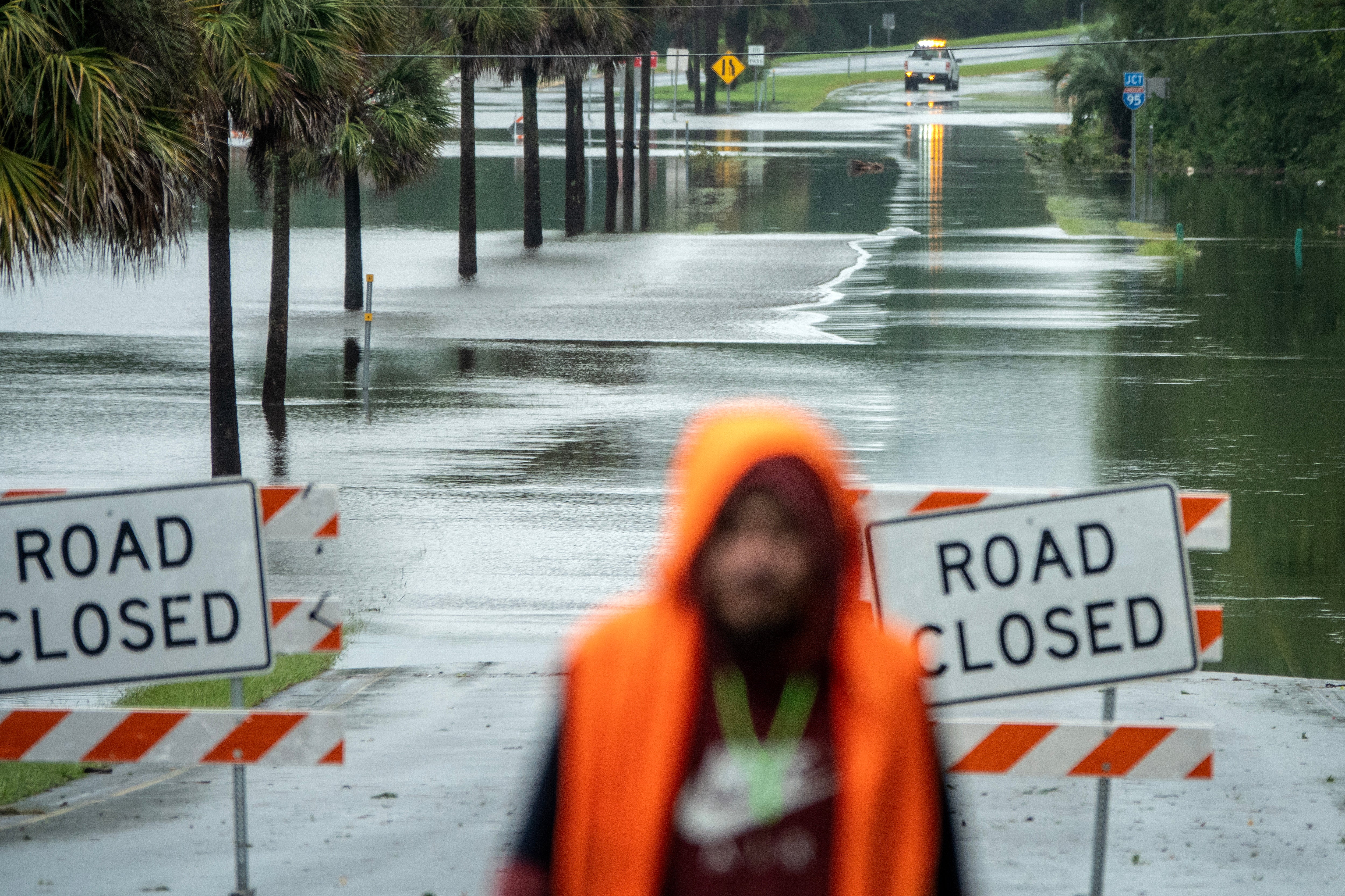 A person walks near a blocked road flooded from Tropical Storm Debby in Ridgeland, South Carolina on Tuesday