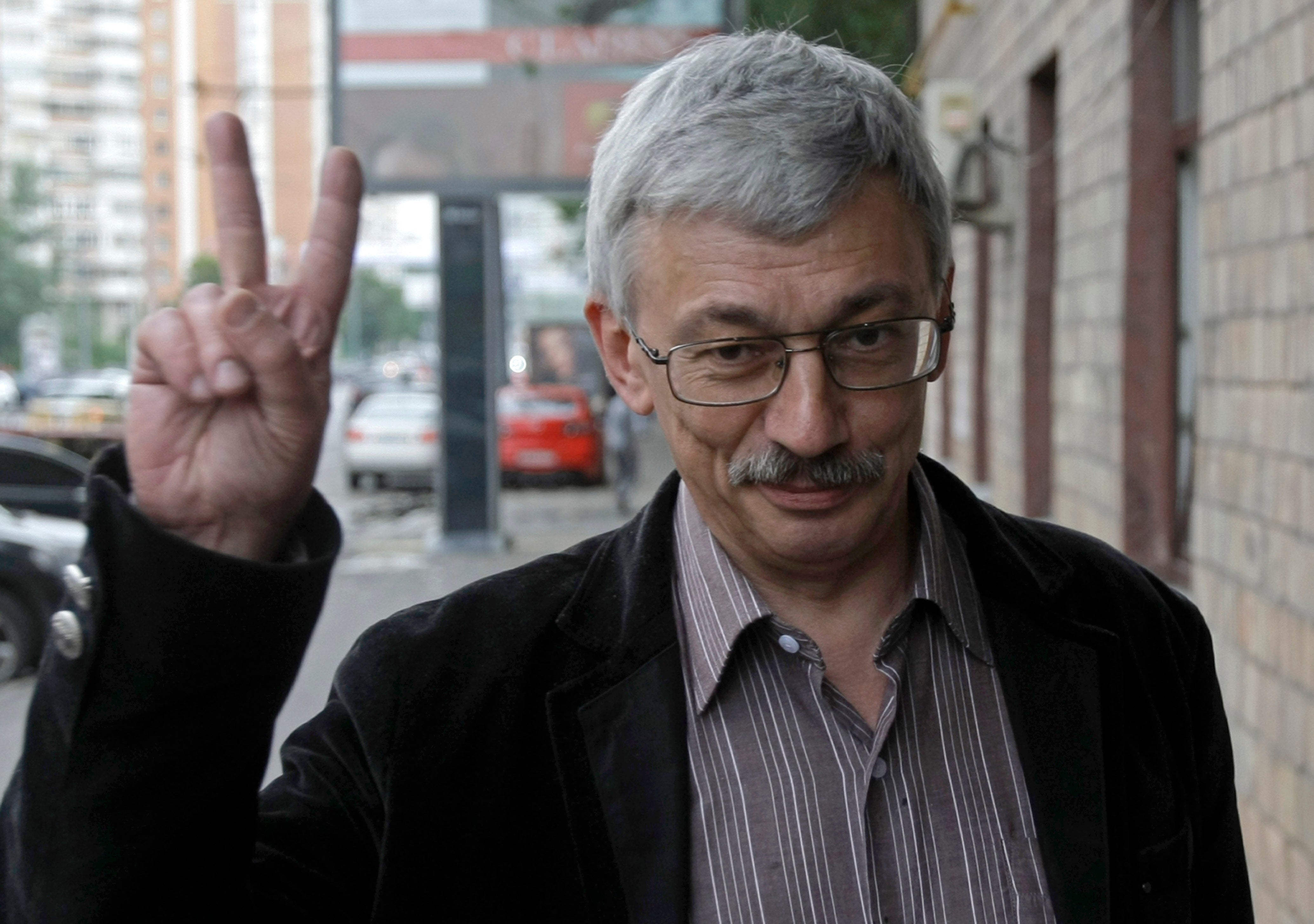 Oleg Orlov gives a victory sign as he walks to a court in Moscow, Russia, Tuesday, 14 June 2011