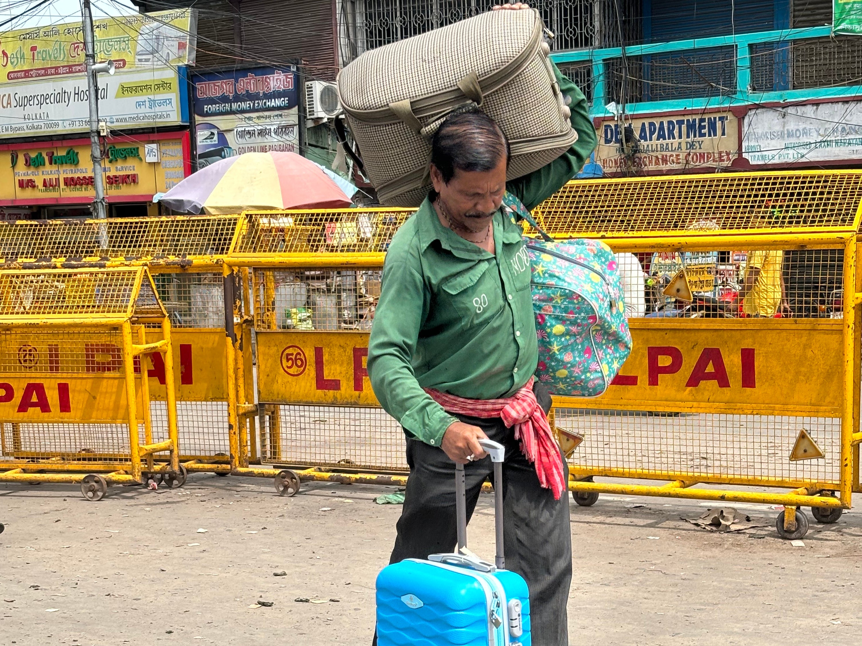 A porter carries the luggage of a Bangladeshi national upon his arrival in India