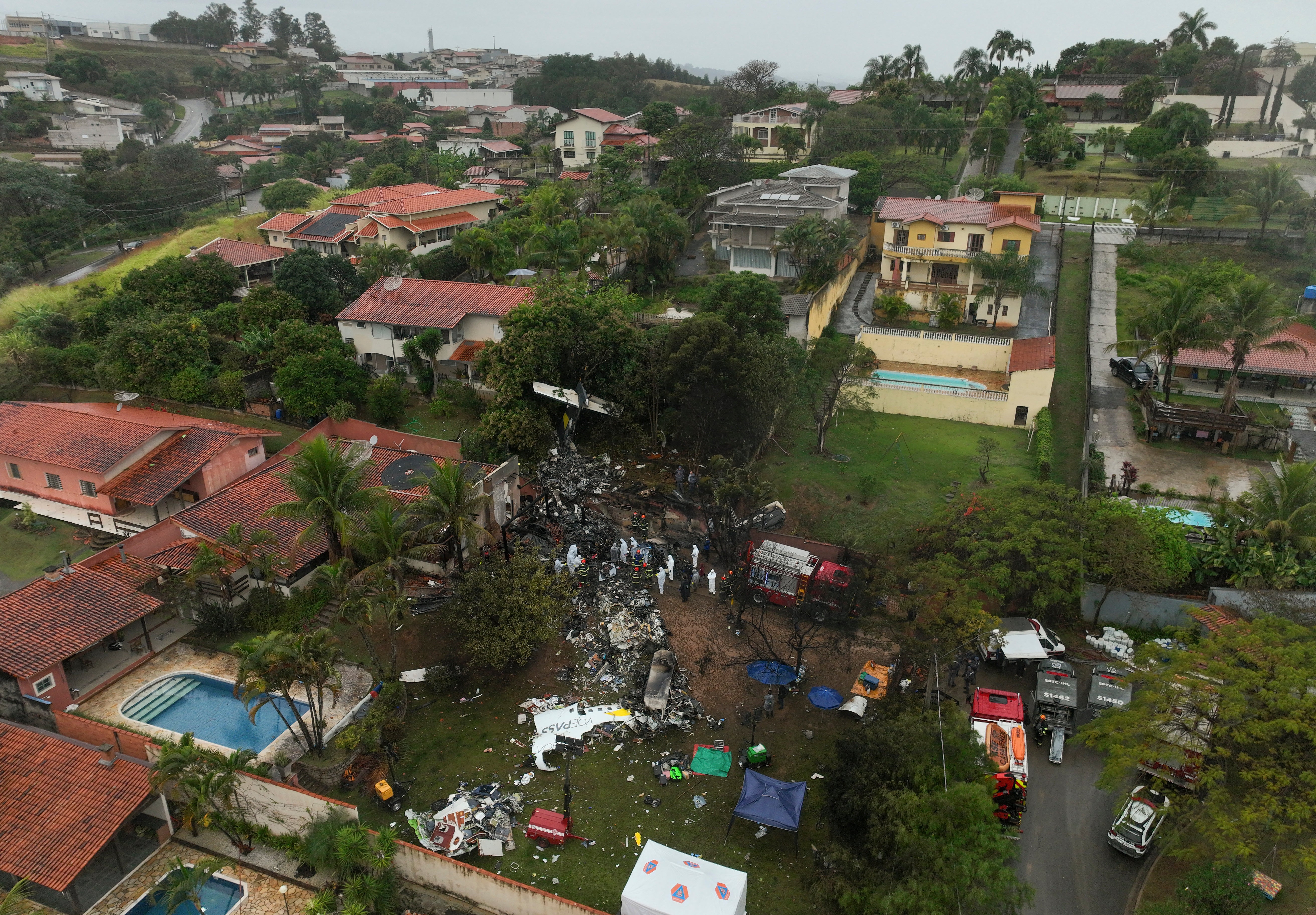 Firefighters and rescue teams work at the site in a residential area where the plane with 62 people on board crashed in Vinhedo