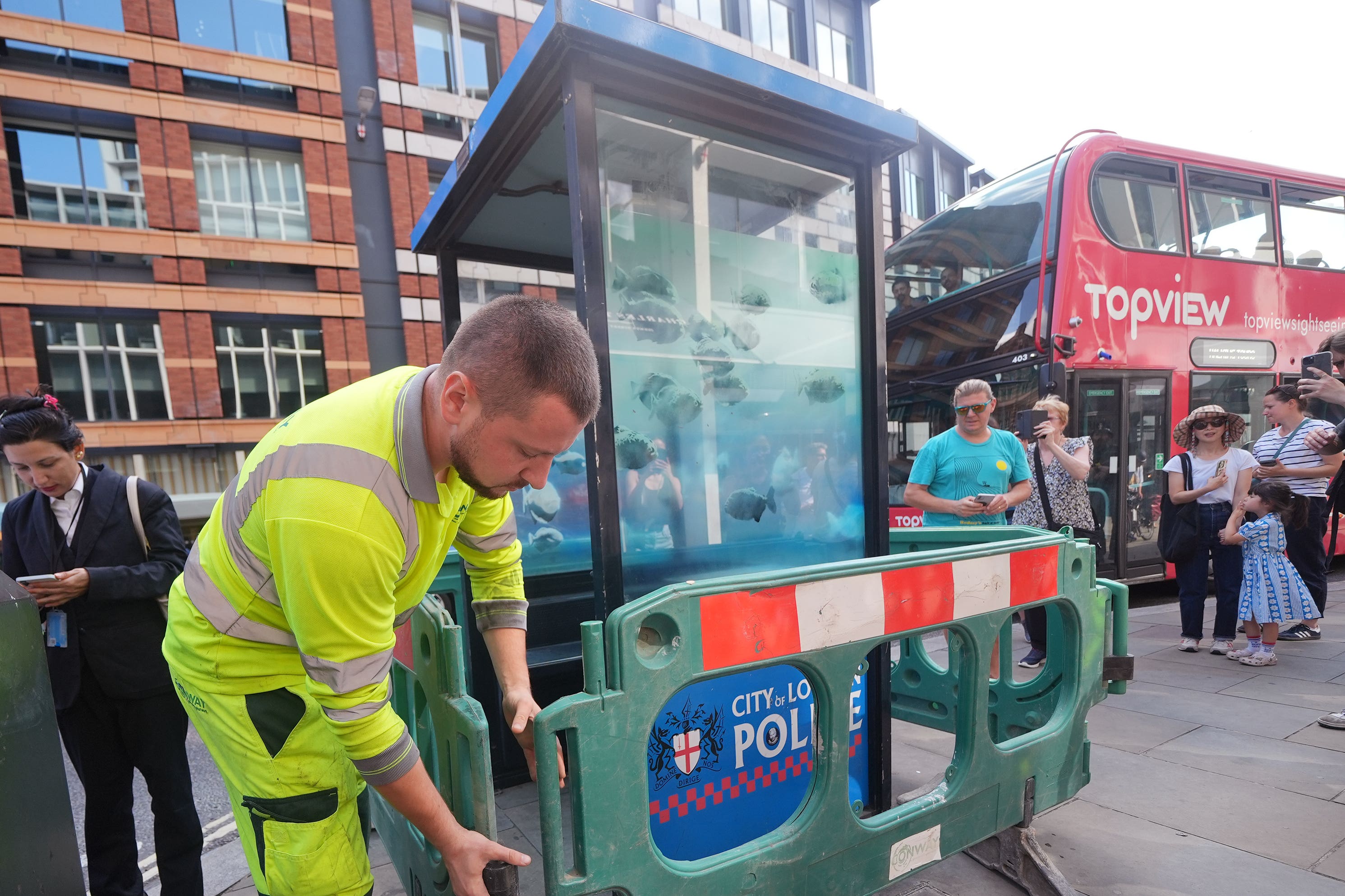 A new design of swimming piranhas by Banksy, which has appeared on a police box in the City of London, is cordoned off by contractors (Yui Mok/PA)