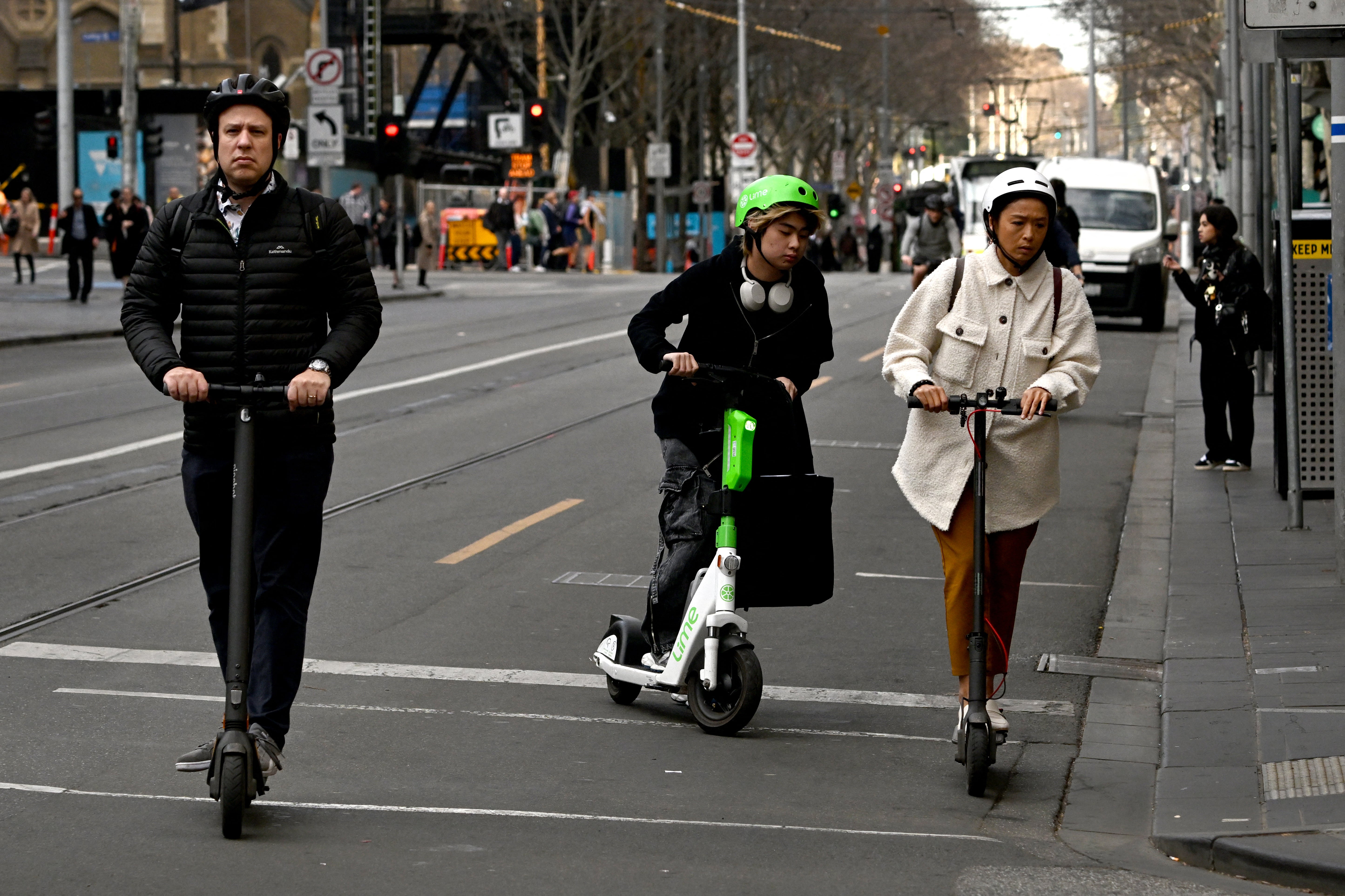 People ride electric scooters in Melbourne’s central business district on 14 August 2024