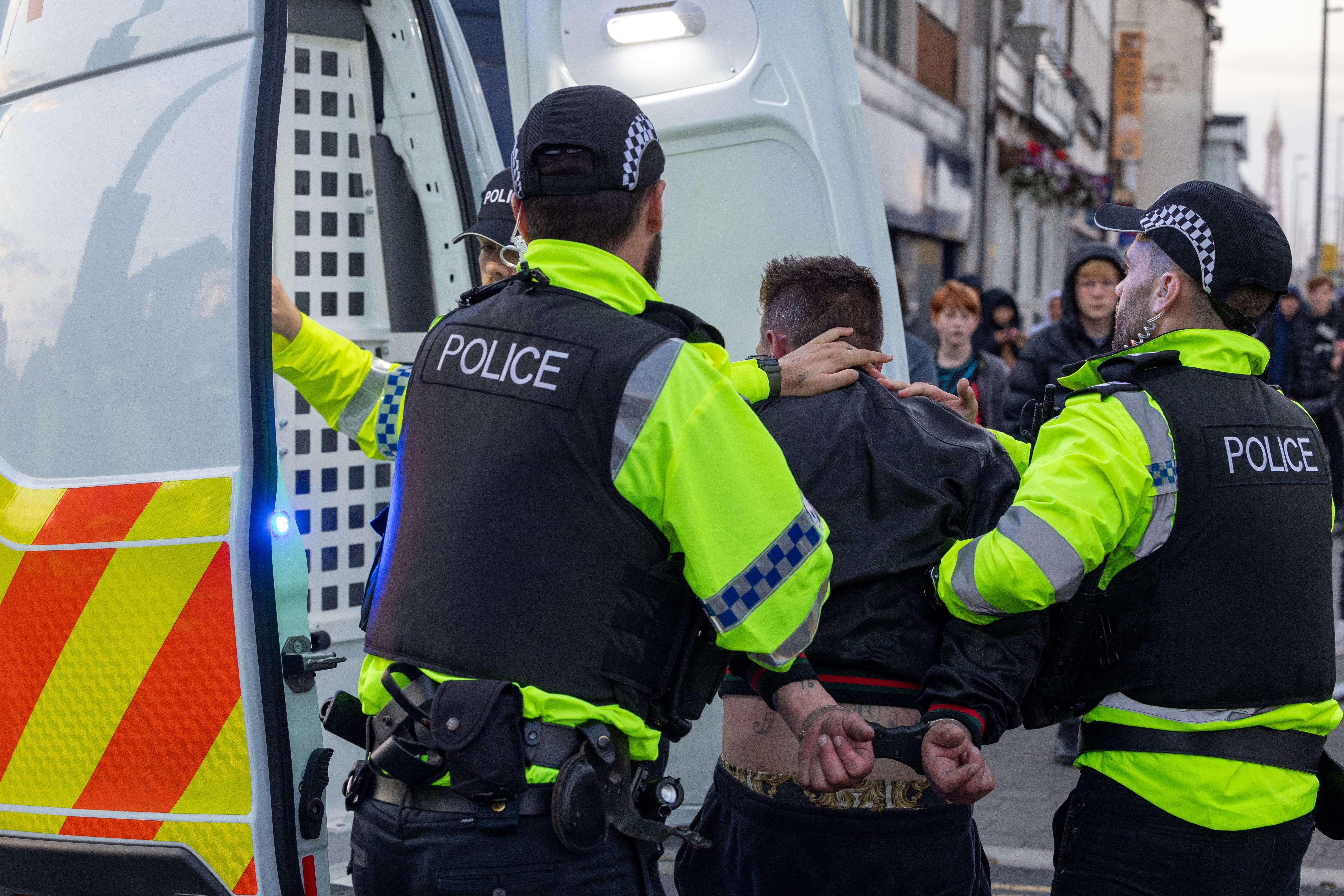 Police officers detaining a person during an anti-immigration protest in Blackpool (PA)