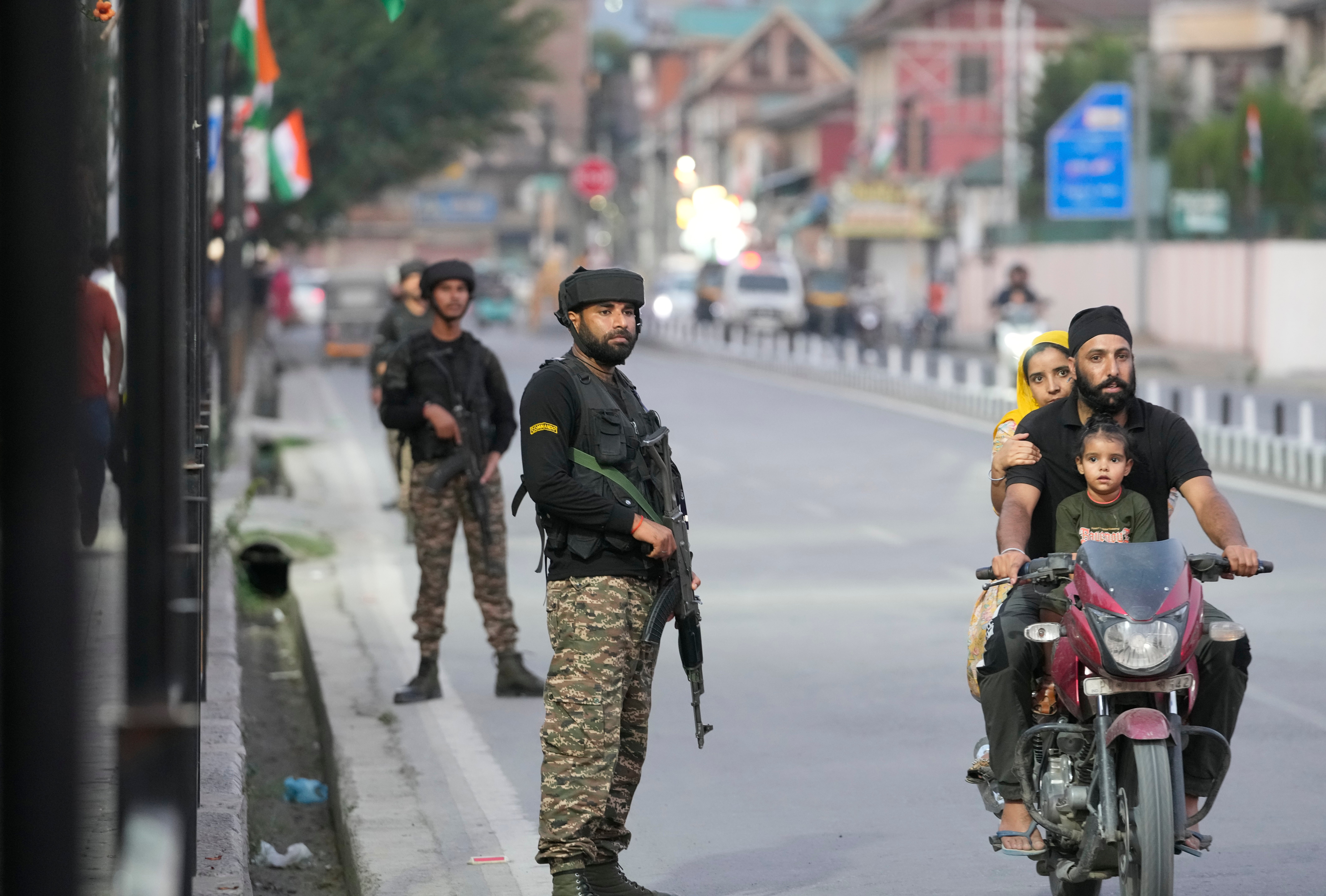 Indian paramilitary soldiers stand guard as a family travels on a motorcycle outside the venue of India’s Independence Day celebrations in Srinagar, Kashmir, on 14 August 2024