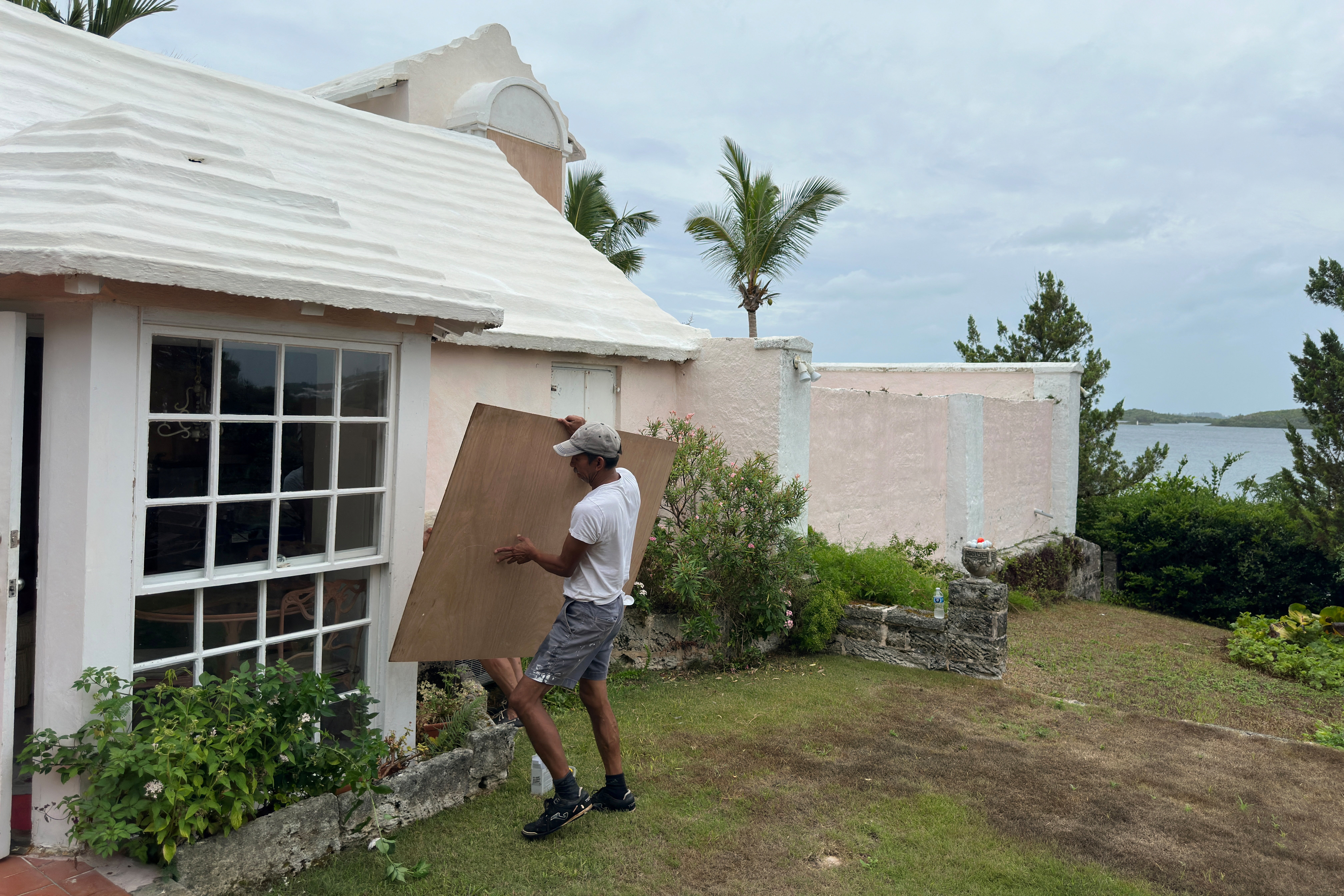 A man boards up his house in Warwick, Bermuda ahead of Hurricane Ernesto, which has strengthened into a Category 2 storm